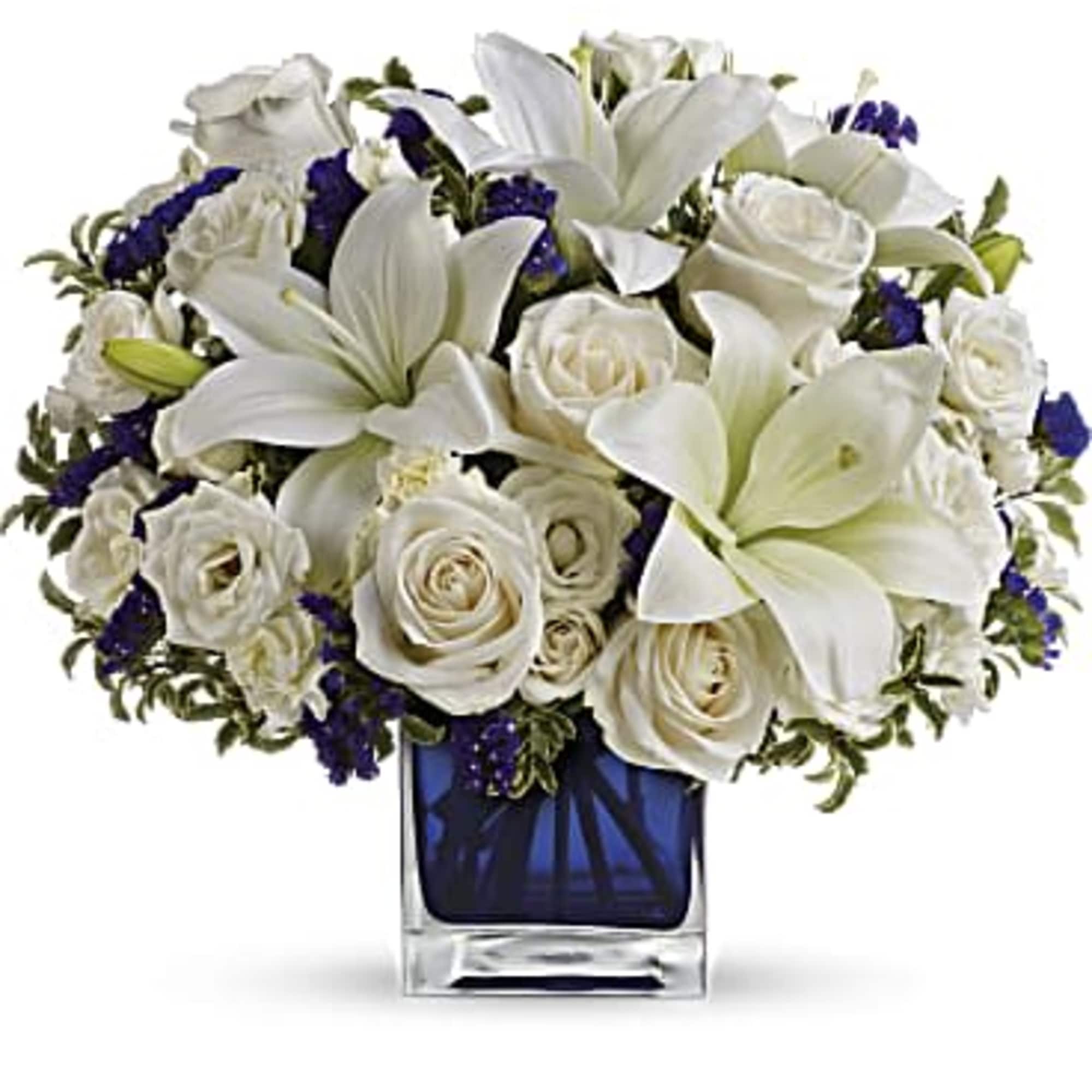 White lilies and roses arranged in a blue glass vase