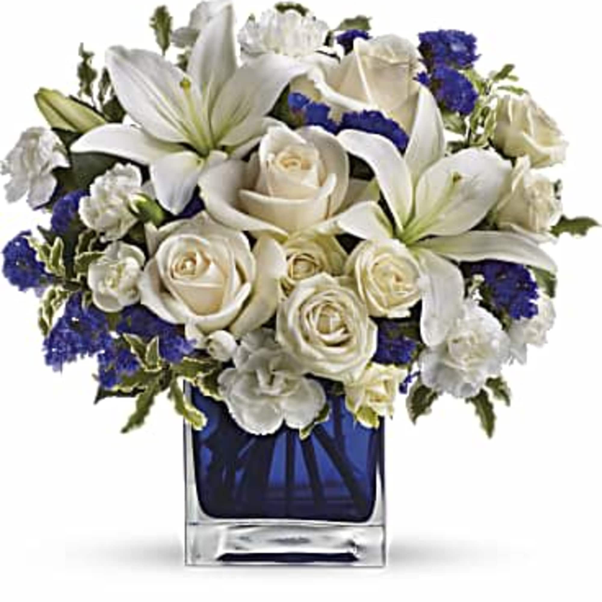 White lilies and roses arranged in a blue glass vase