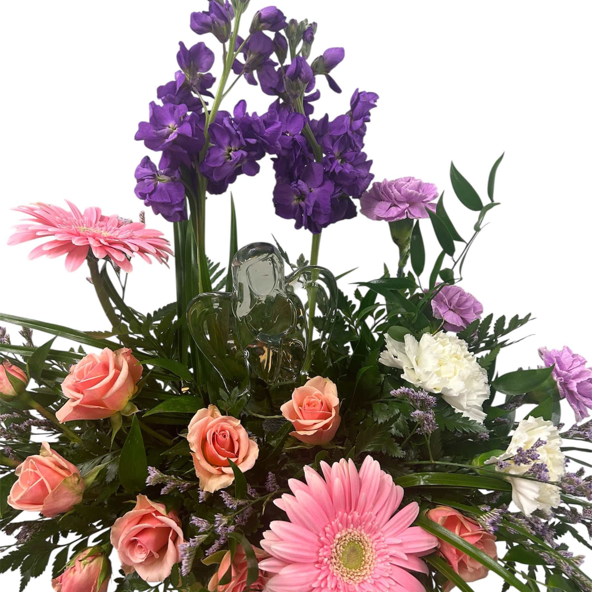 Soft pink gerbera daisies and peach-pink roses surround a clear glass angel