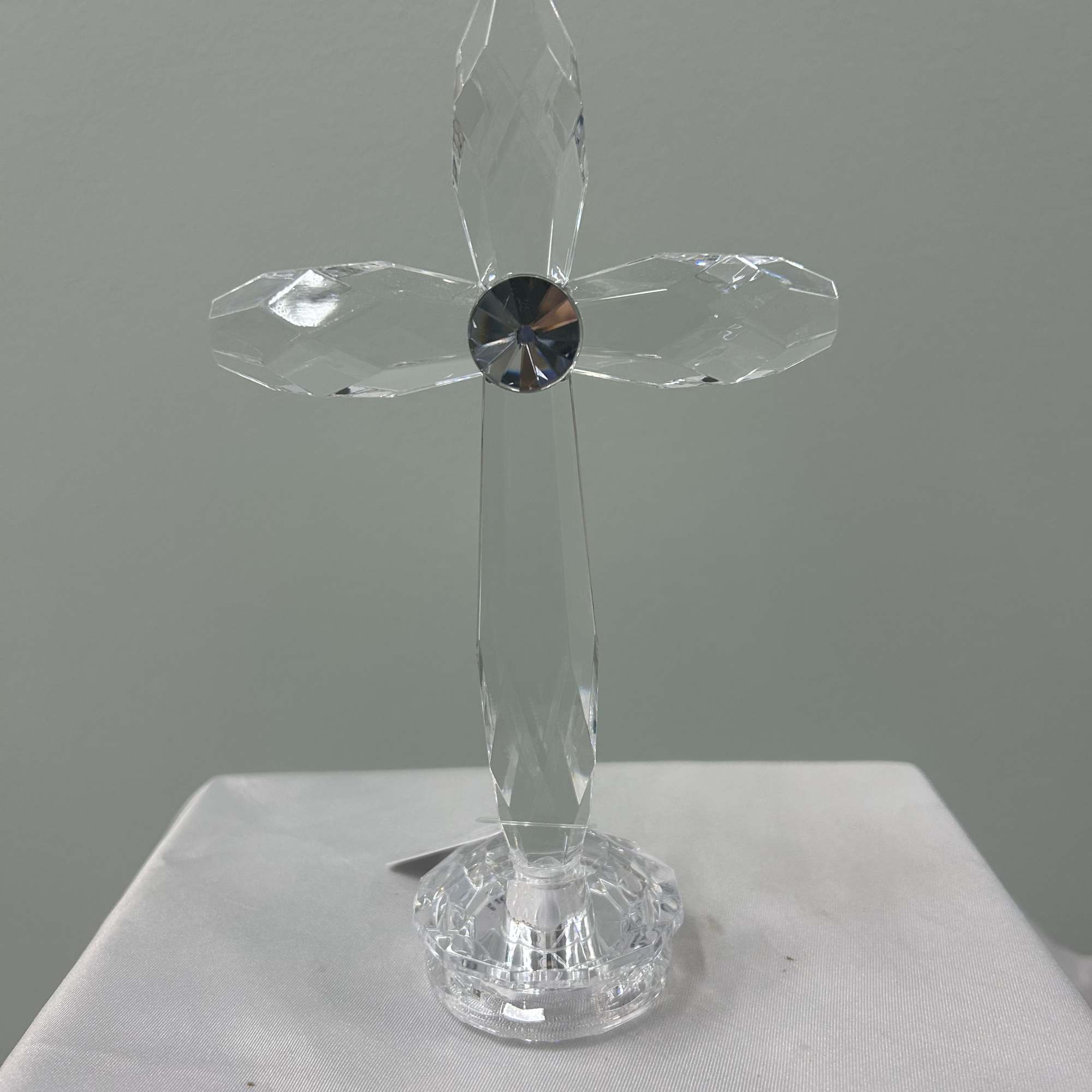 A serene white-and-green sympathy arrangement centered around a crystal cross keepsake creates