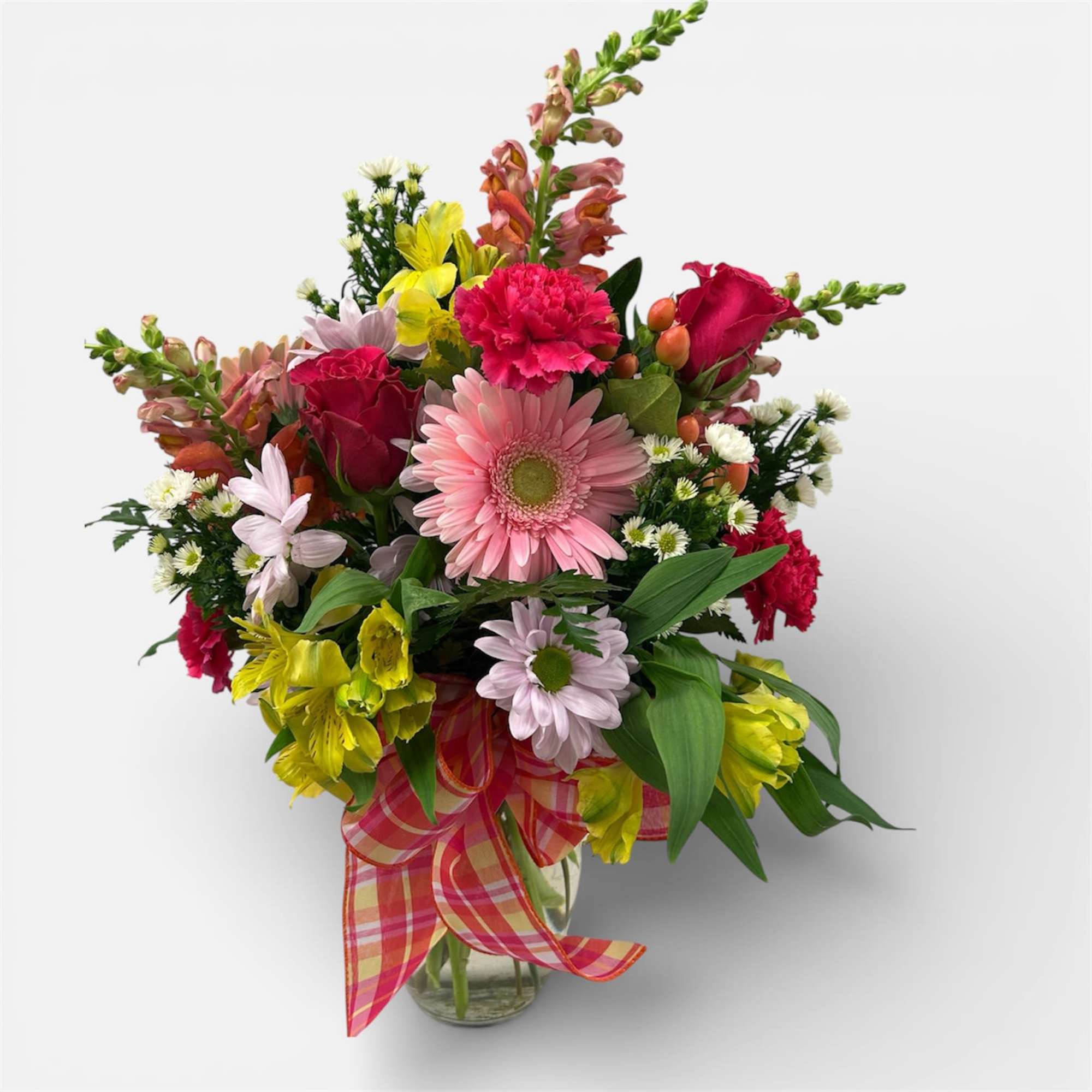 A clear vase designed using a variety of beautiful vibrant colored blooms.