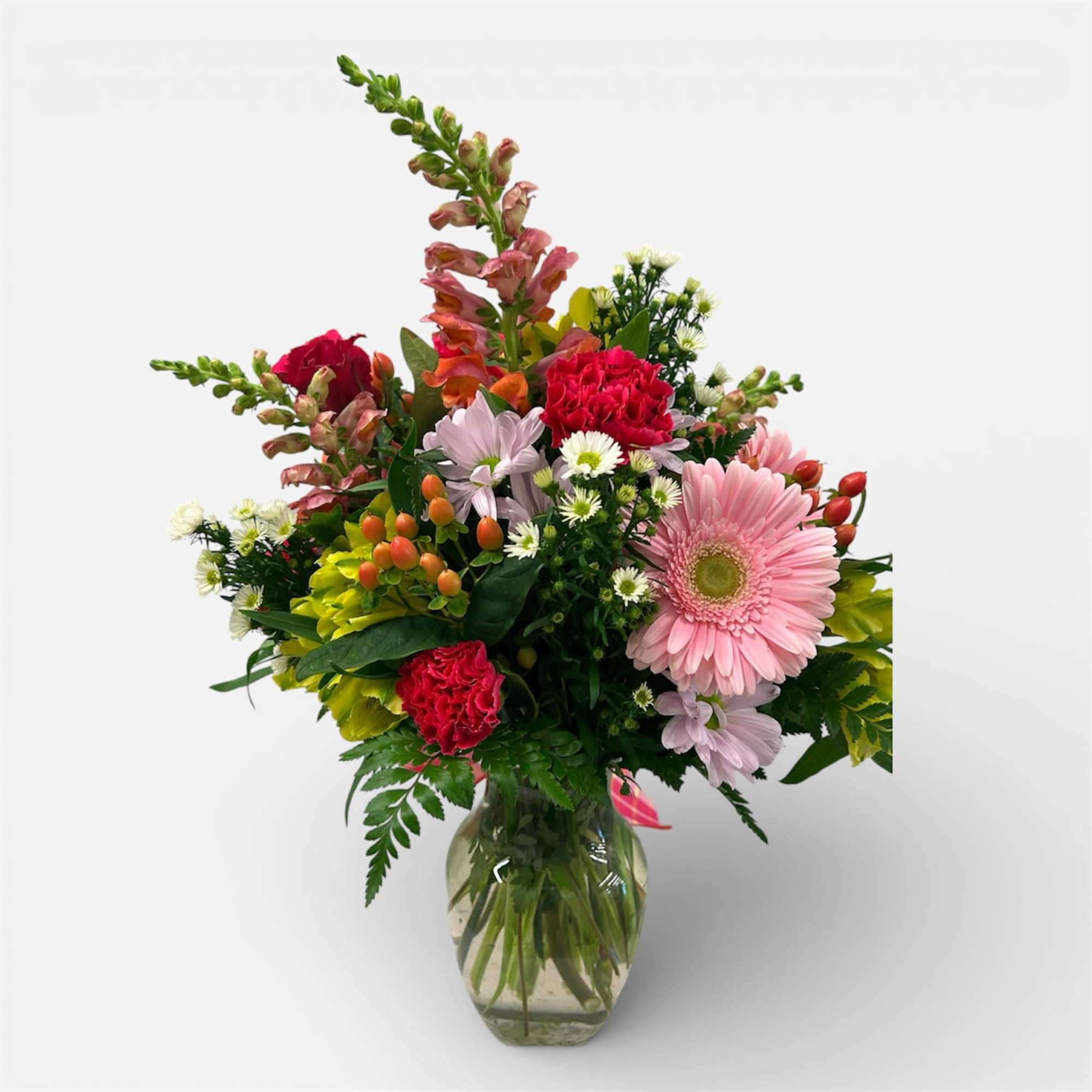 A clear vase designed using a variety of beautiful vibrant colored blooms.