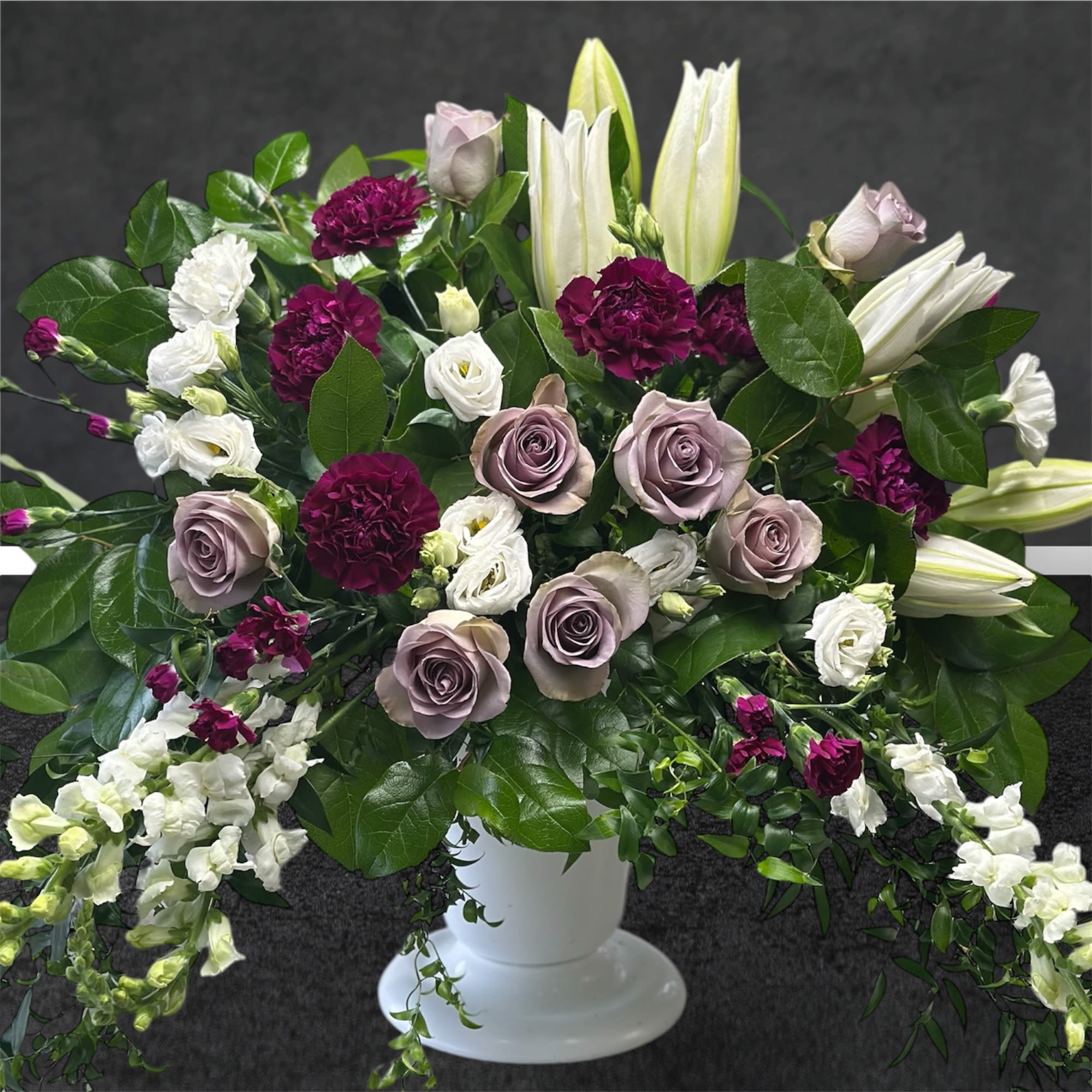 Mixed bouquet in a white pedestal vase with roses, lilies, and carnations