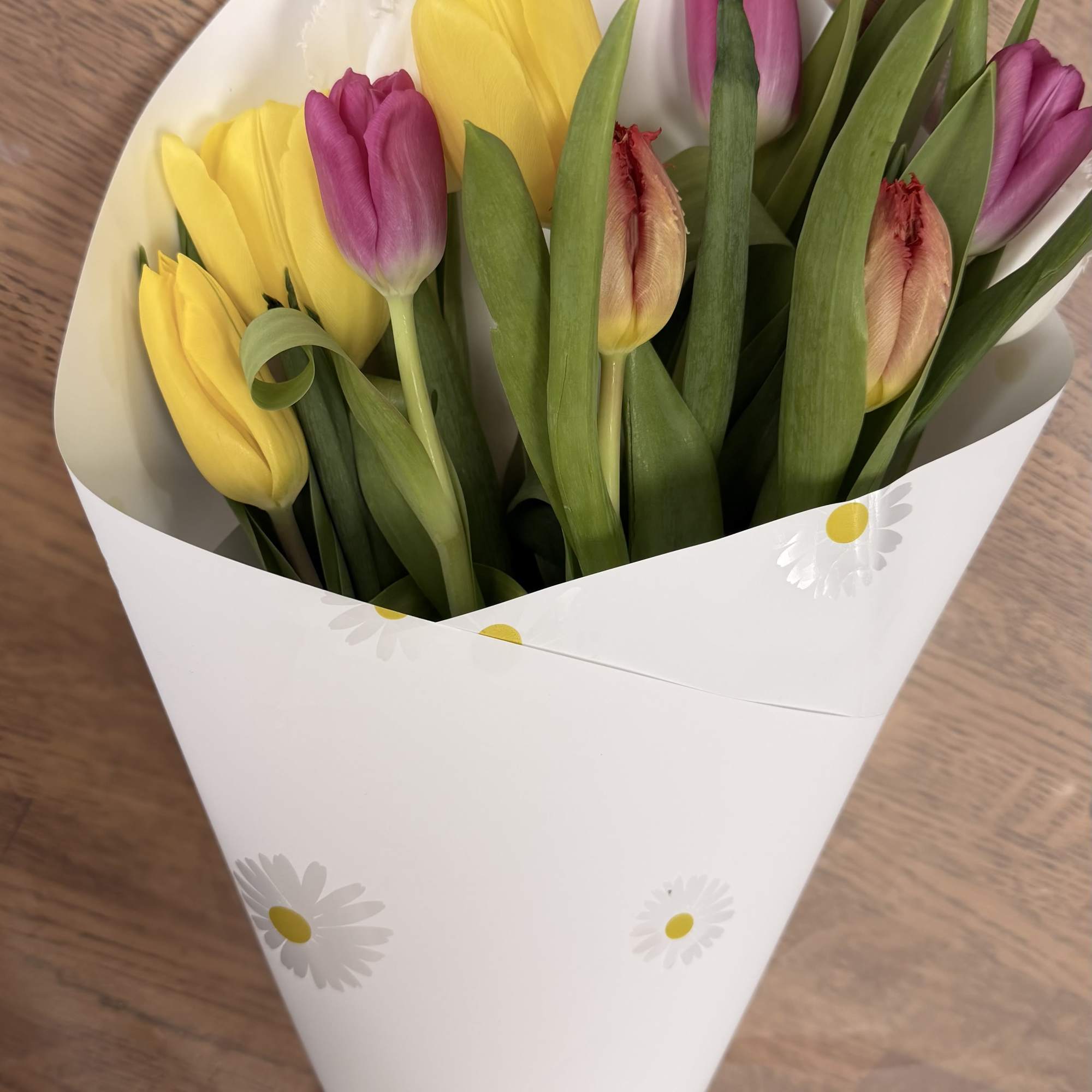 Bouquet of yellow and pink tulips wrapped in white paper