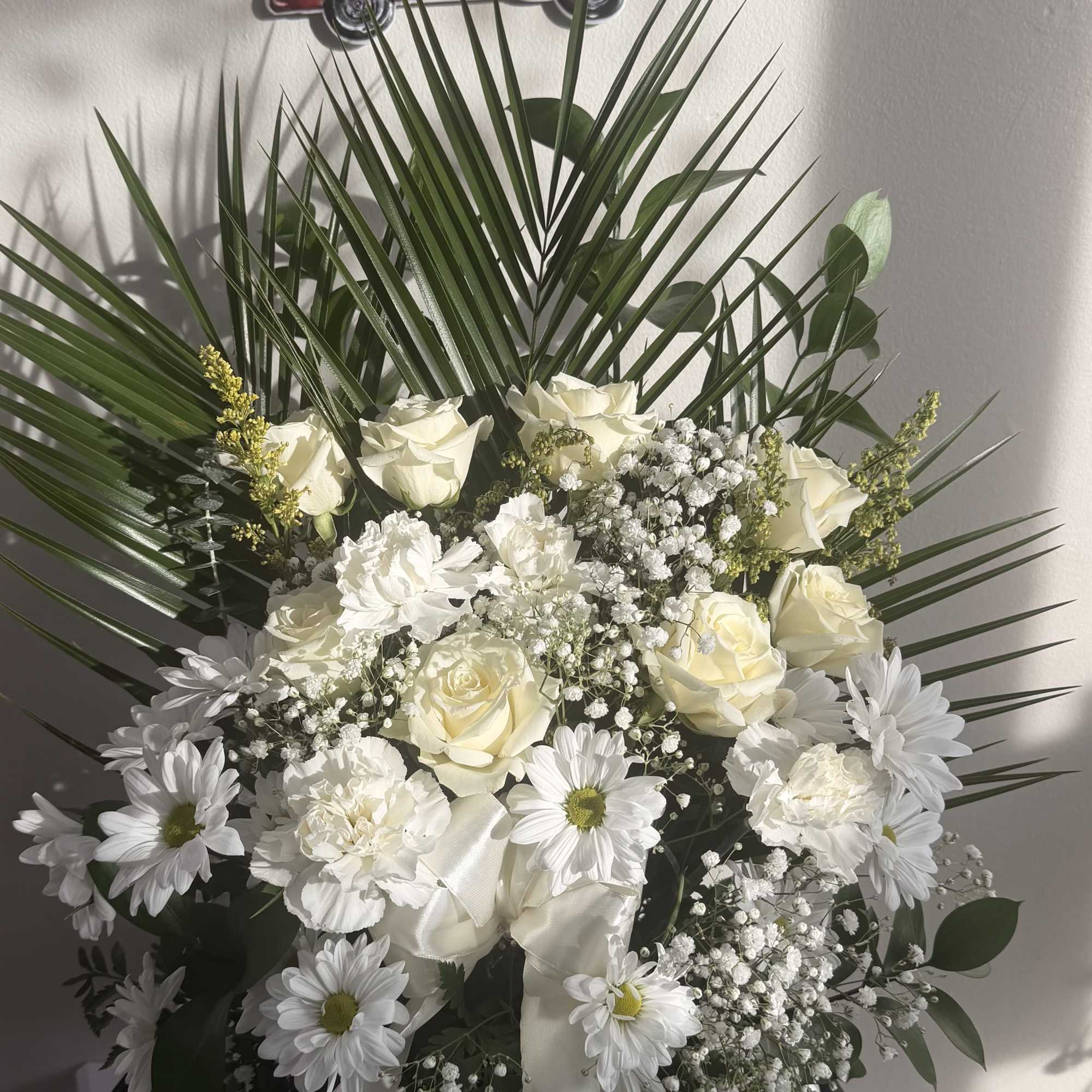 White floral arrangement with roses and daisies in a white container