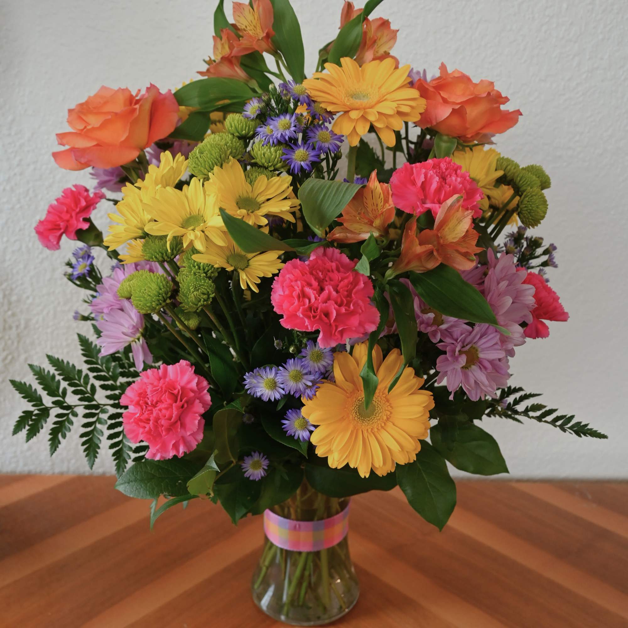 This bright and cheerful bouquet is bursting with colorful daisies, roses, gerbera