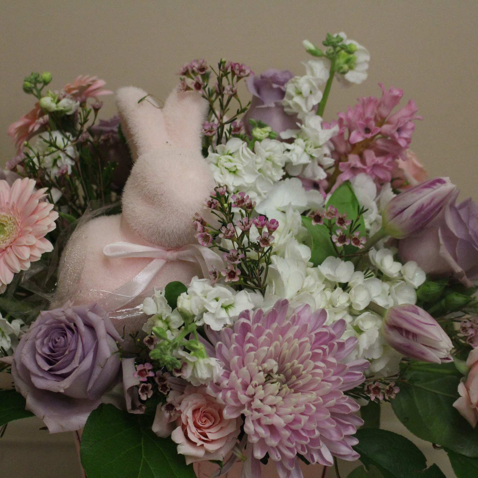 A cheerful pink bunny is nestled among a beautiful field of pastel