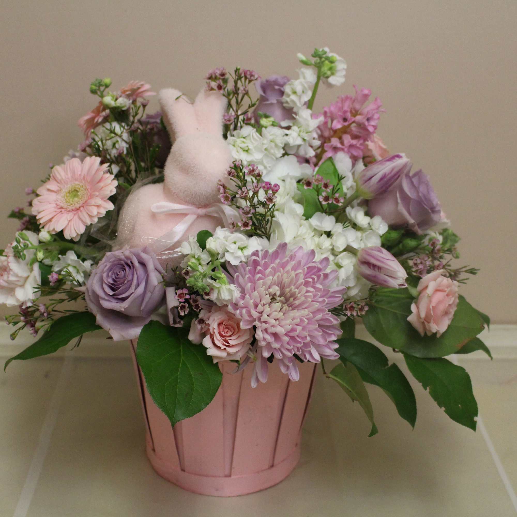 A cheerful pink bunny is nestled among a beautiful field of pastel