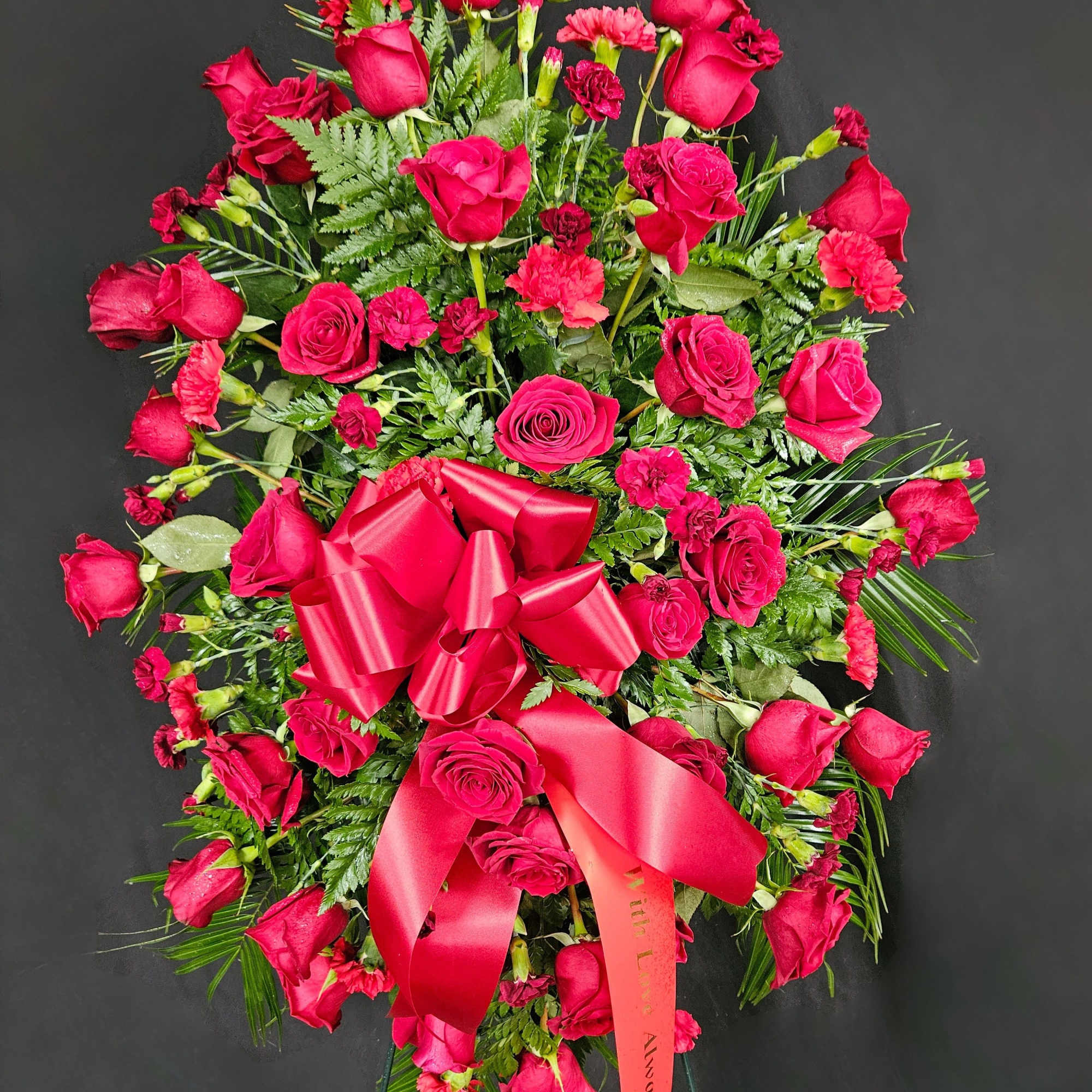 A standing spray of red roses and red carnations on a bed