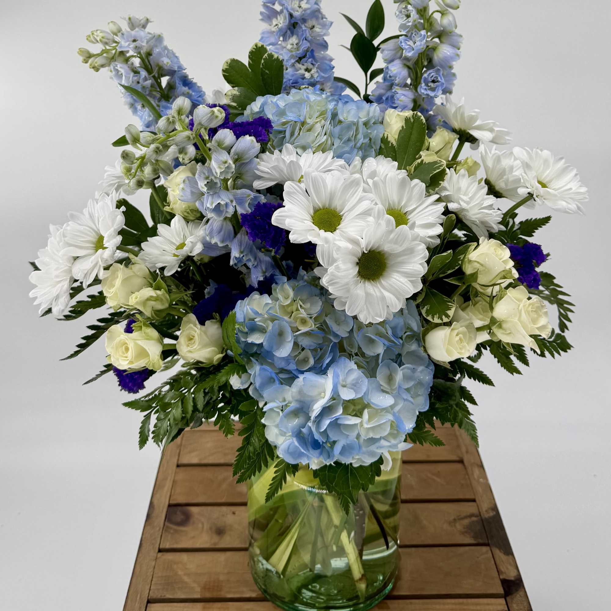 Immerse yourself in a tranquil oasis with our enchanting Sky-Blue flower arrangement