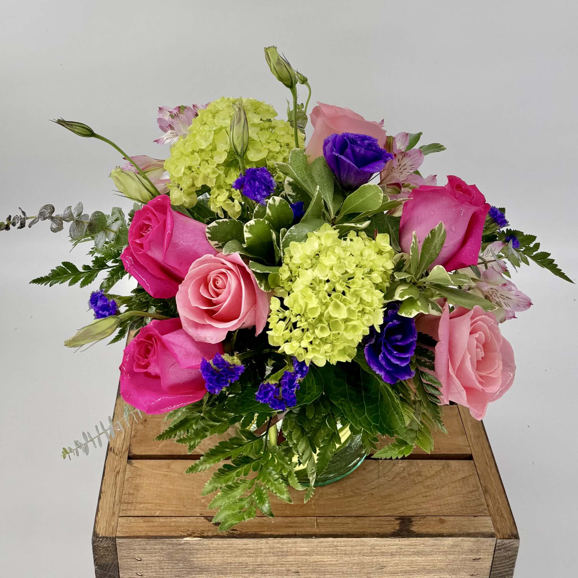 Vibrant flower arrangement featuring hot pink and soft pink roses, lush green