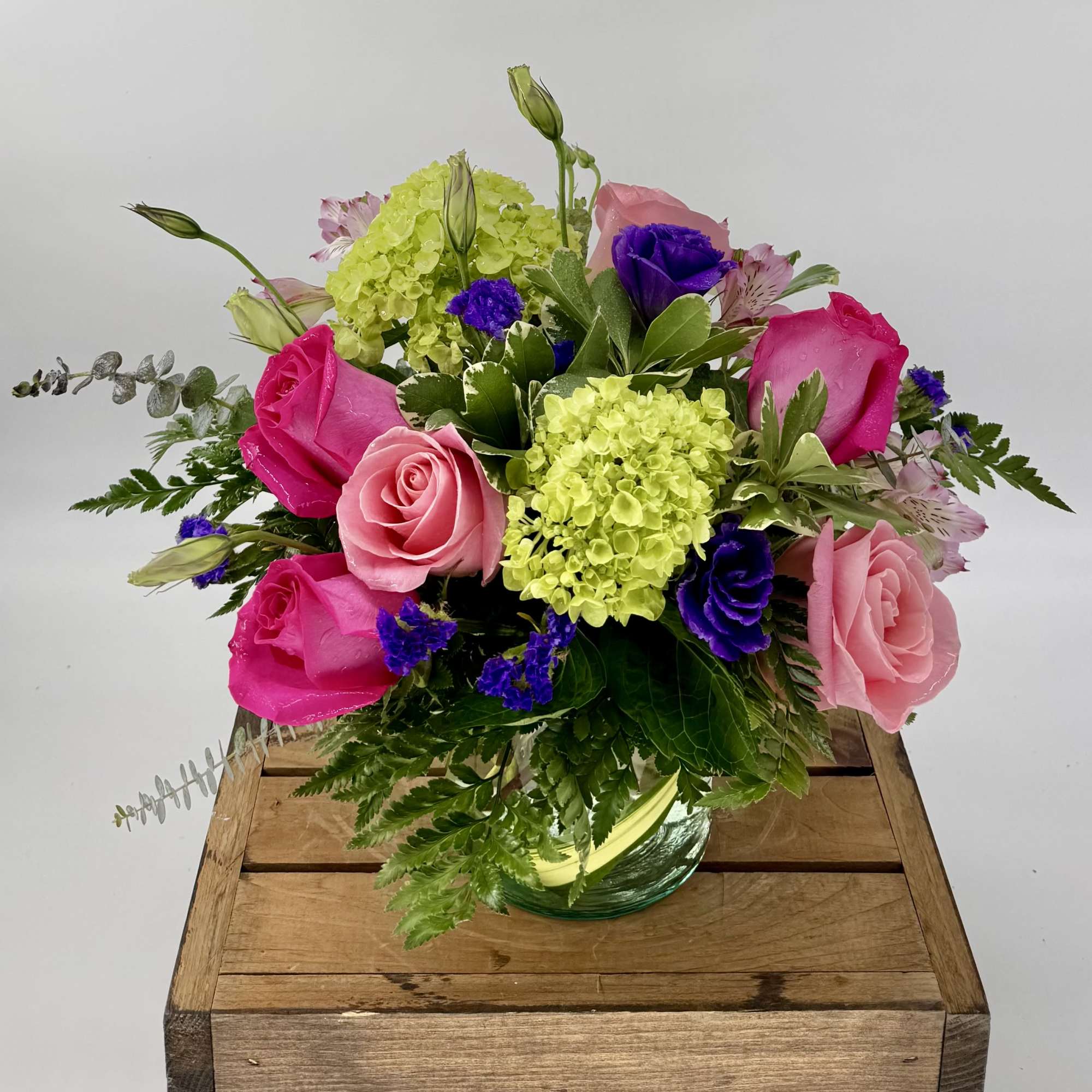 Vibrant flower arrangement featuring hot pink and soft pink roses, lush green