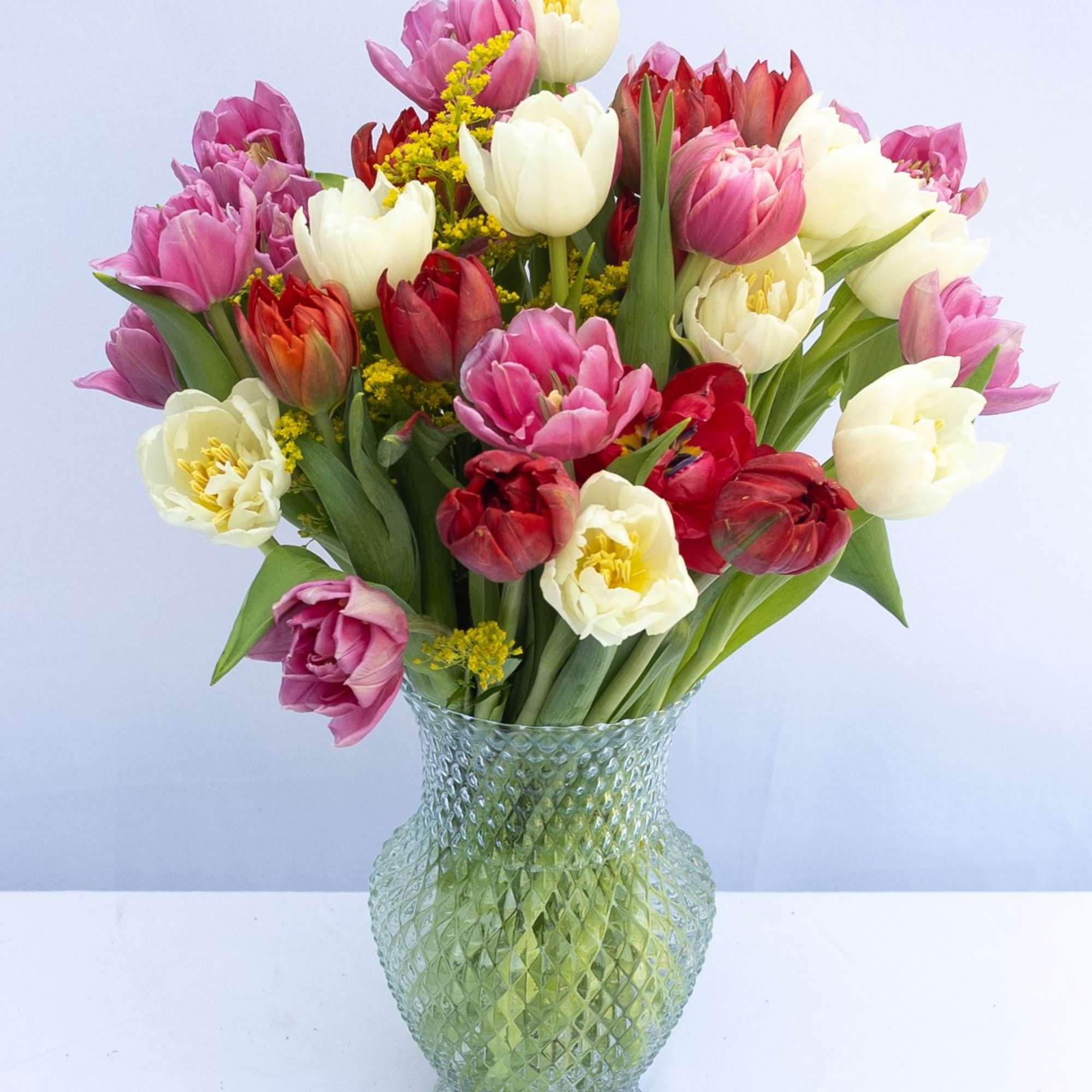 Bouquet of pink, white, and red tulips in a glass vase