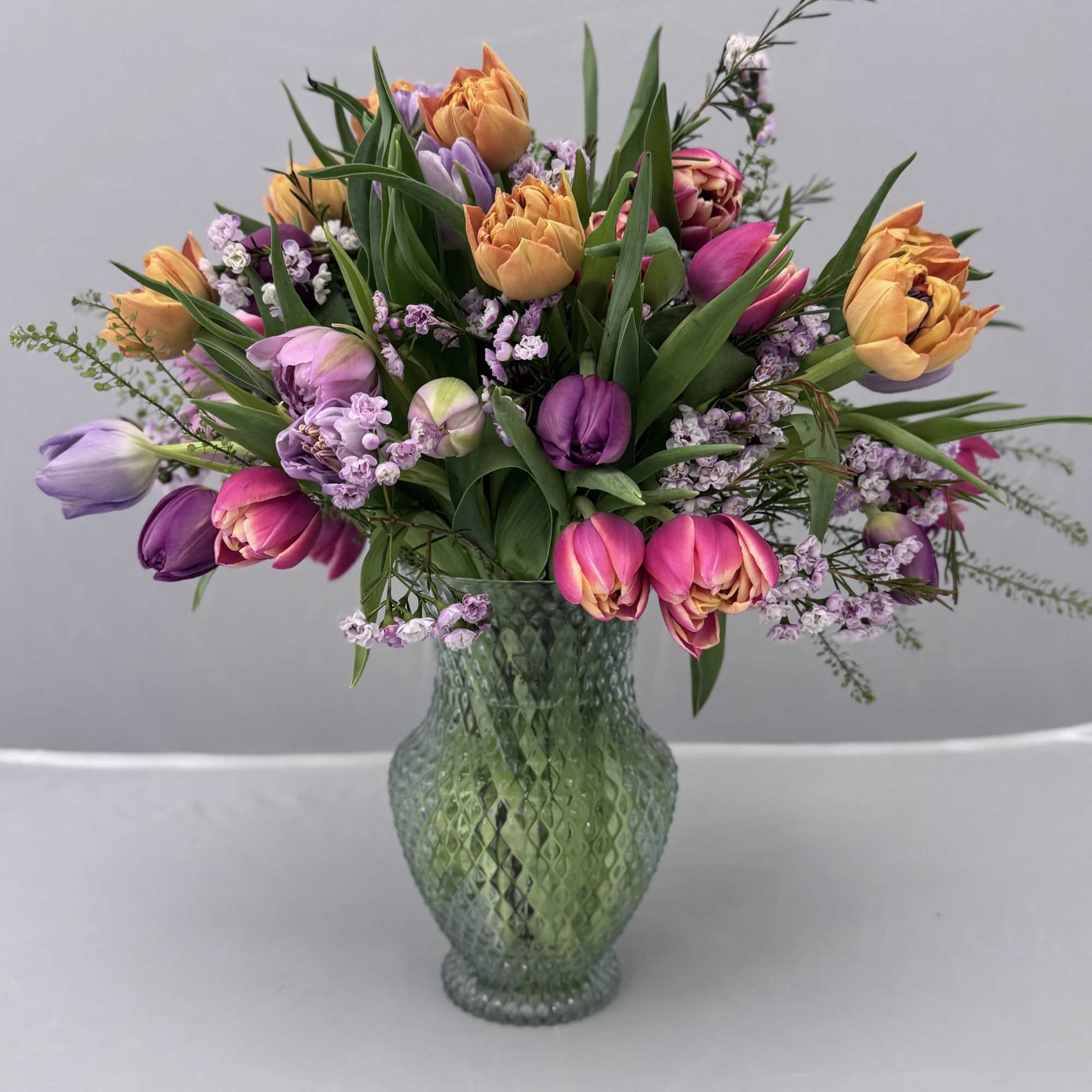Bouquet of multicolored tulips in a green glass vase