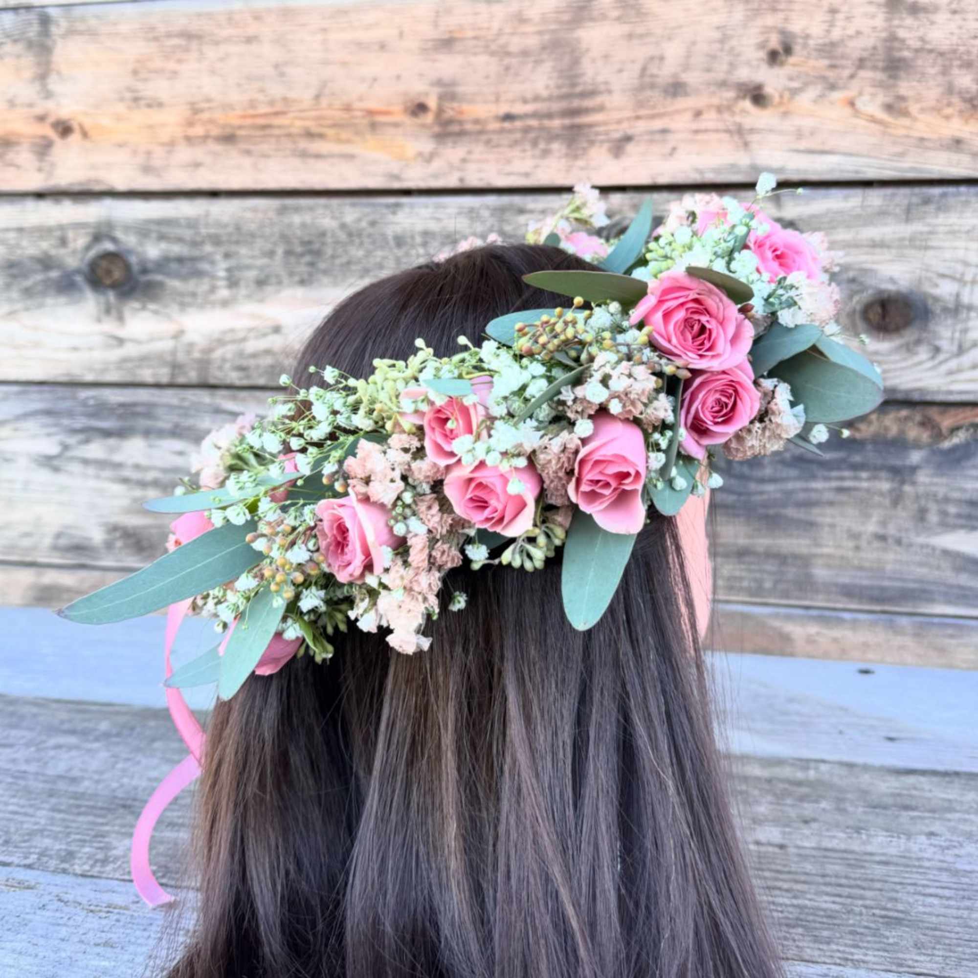 A  floral crown featuring soft pink roses, baby's breath, and eucalyptus