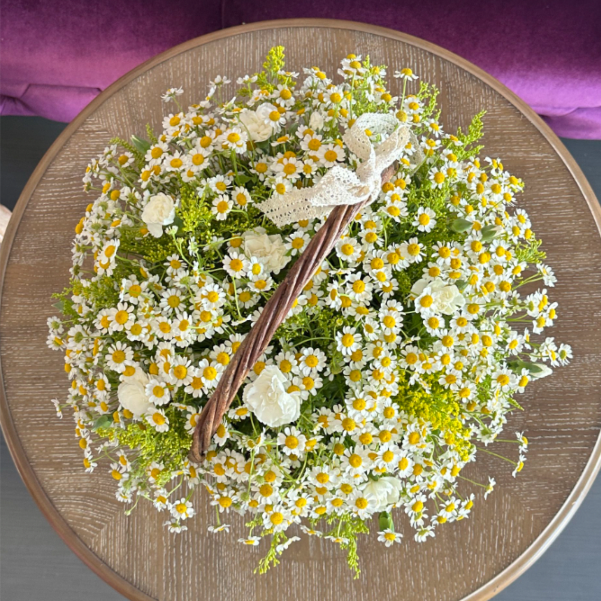 This charming basket arrangement features an abundance of pure daisies, symbolizing innocence