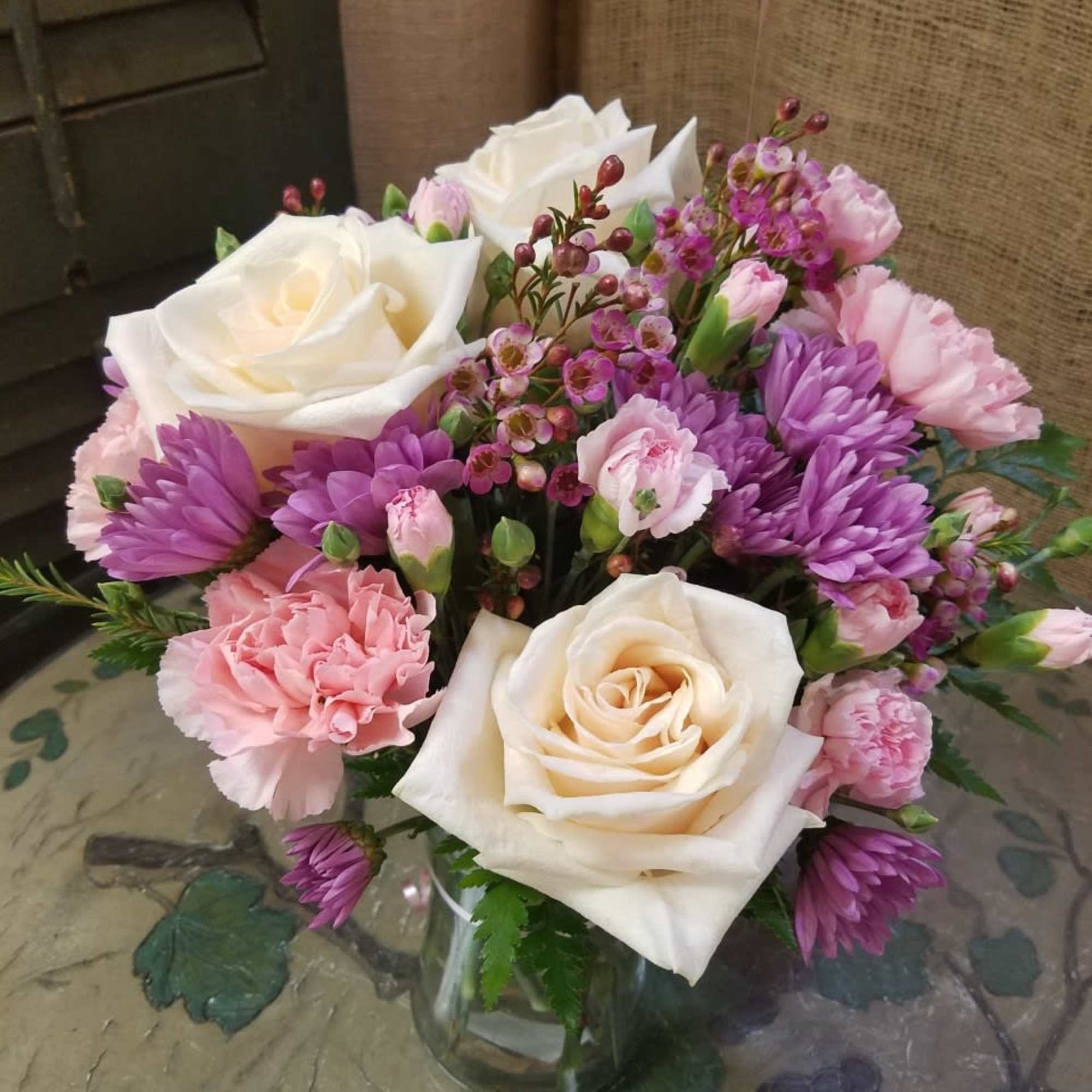 Short vase with roses, daisies and miniature carnations. Designed at Haehn Florist