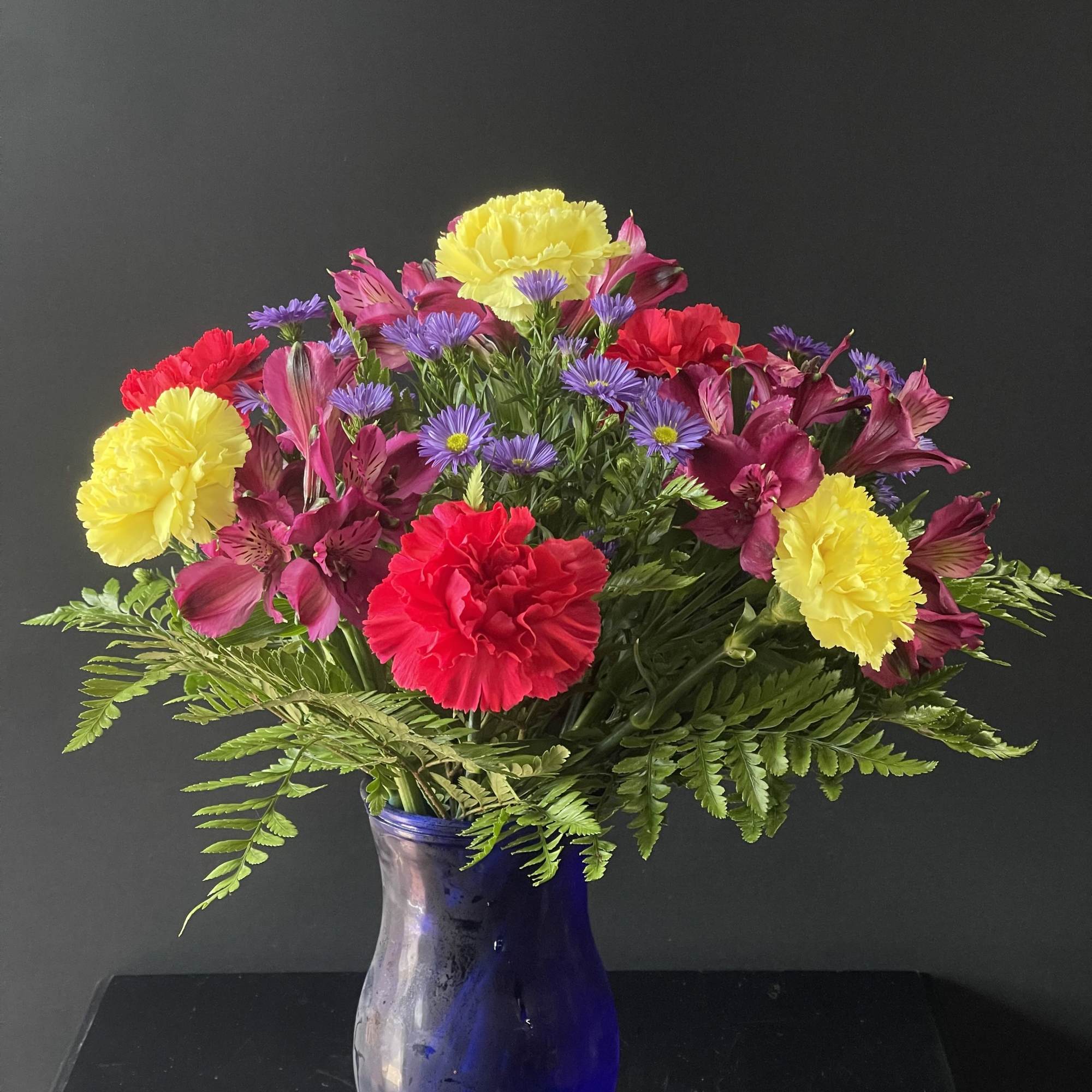 A fun and bright arrangement with carnations, alstroemeria, and monte casino.