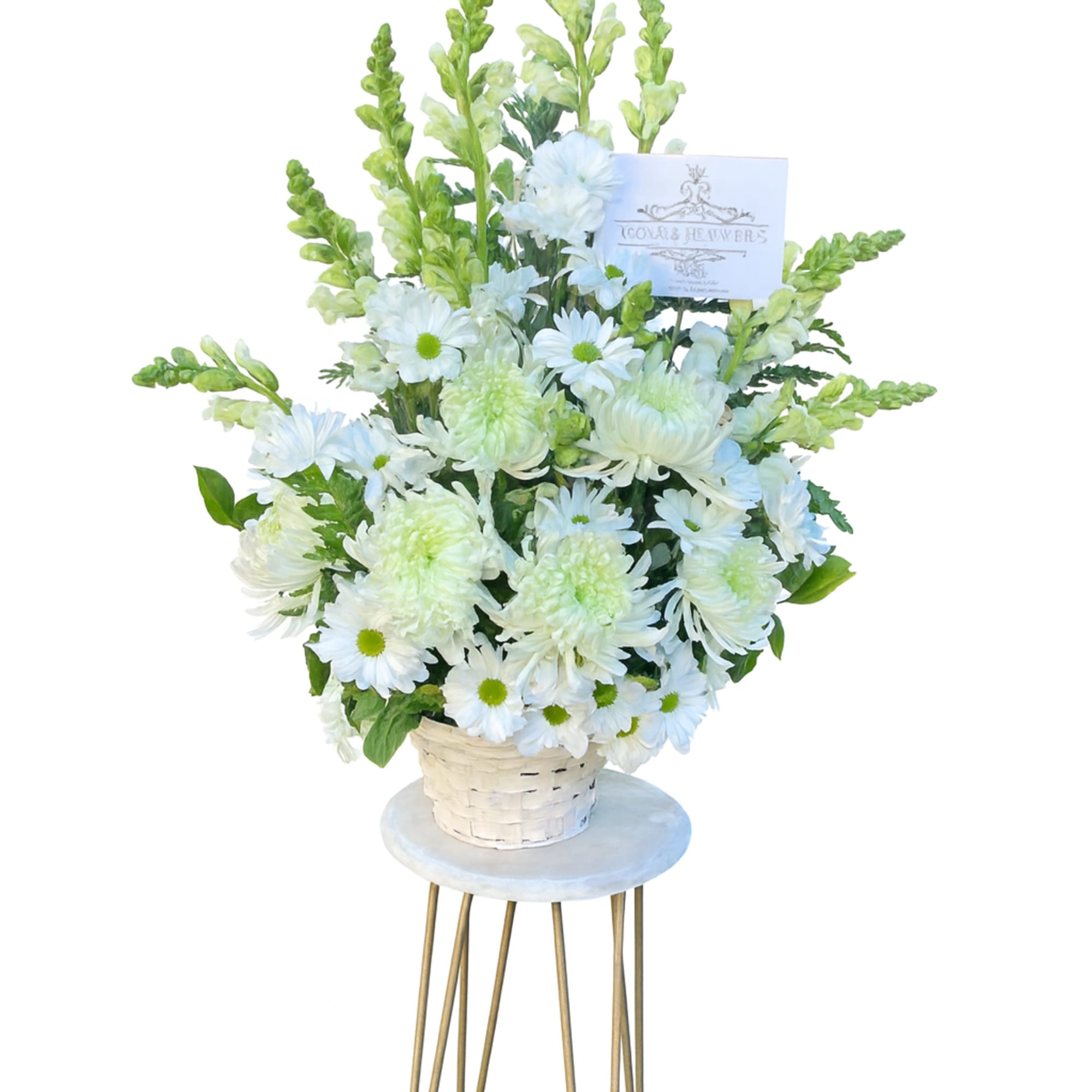 Tall white and green flower basket arrangement with card displayed on a small round stand