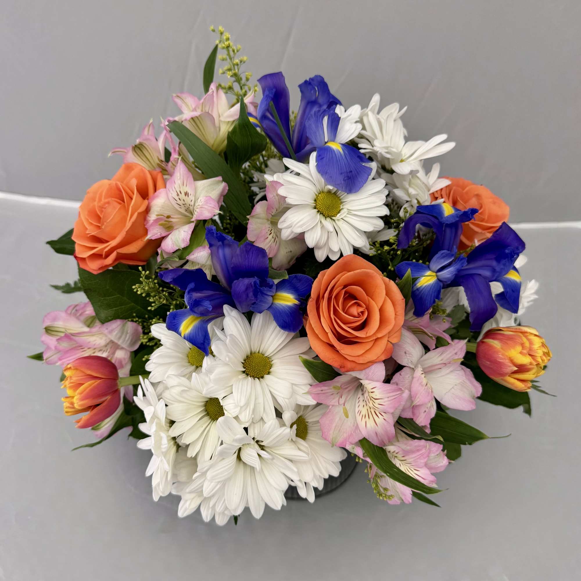 Mixed bouquet with orange roses, white daisies, blue irises, and pink lilies