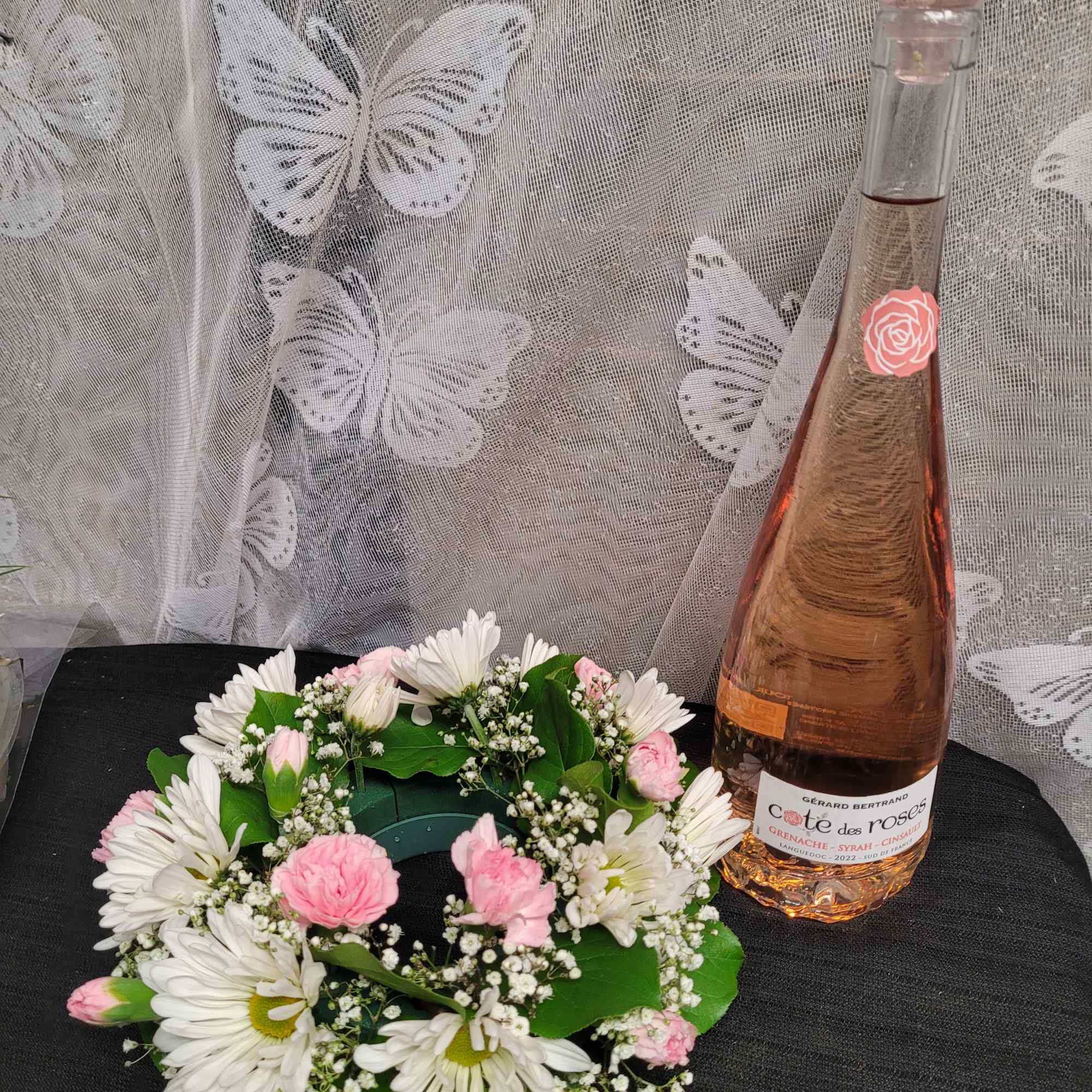 A tall glass bottle of ros&eacute; rises from the center of a
