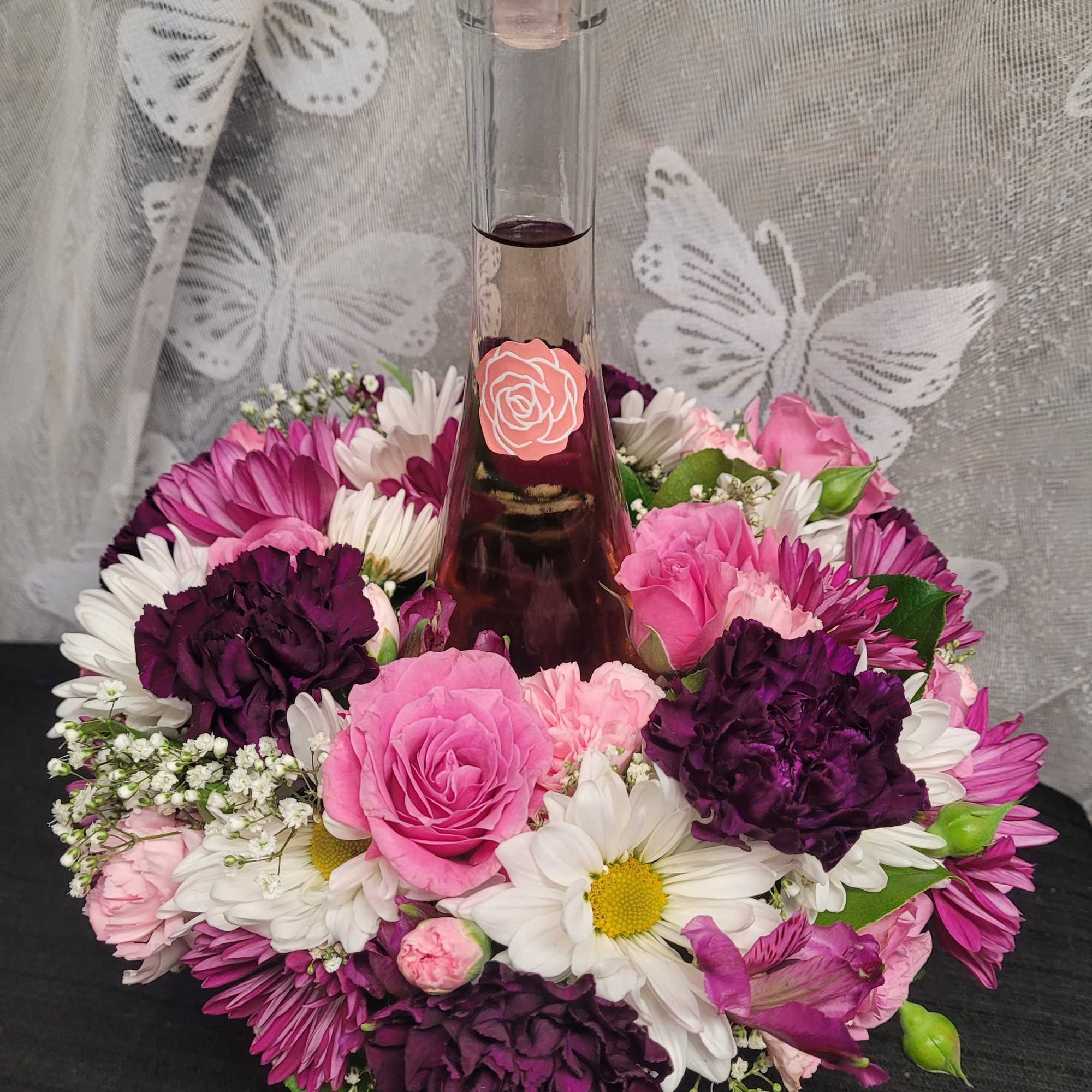 A tall glass bottle of ros&eacute; rises from the center of a