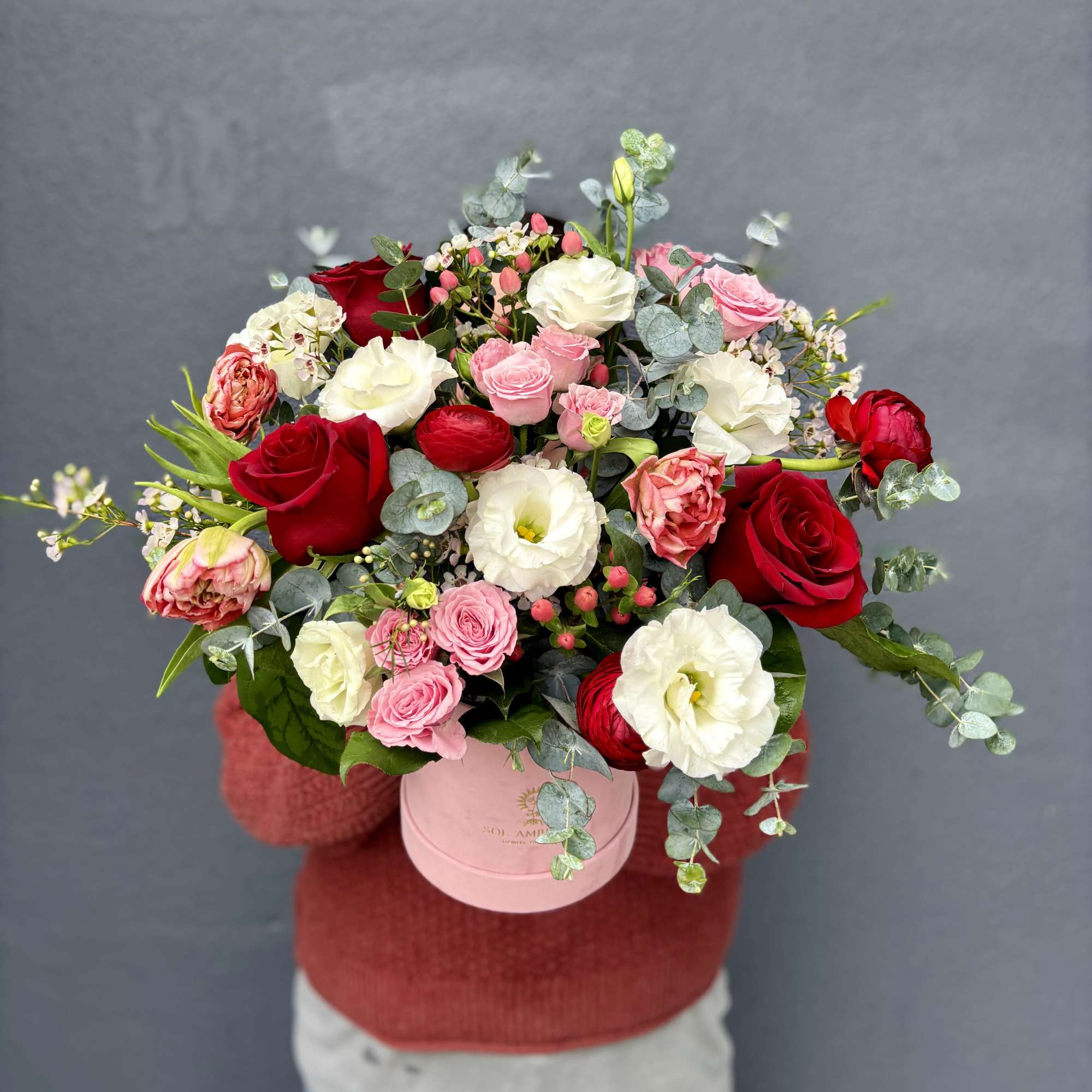 Mixed bouquet of red, pink, and white roses in a pink hatbox