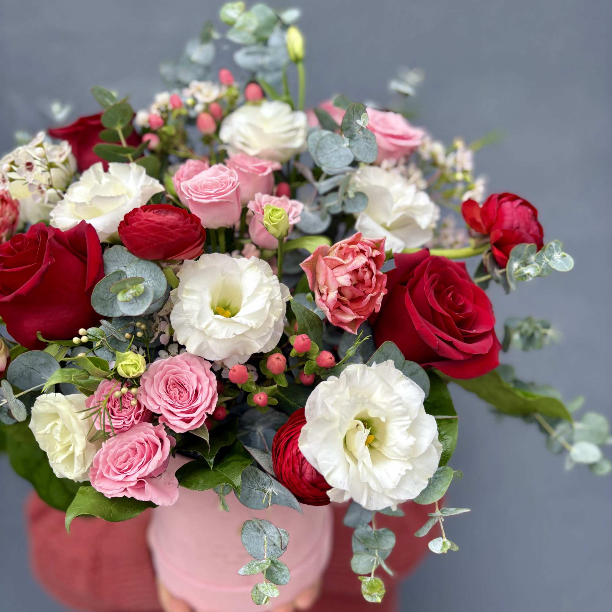Bouquet of red, pink, and white roses with eucalyptus in a pink vase
