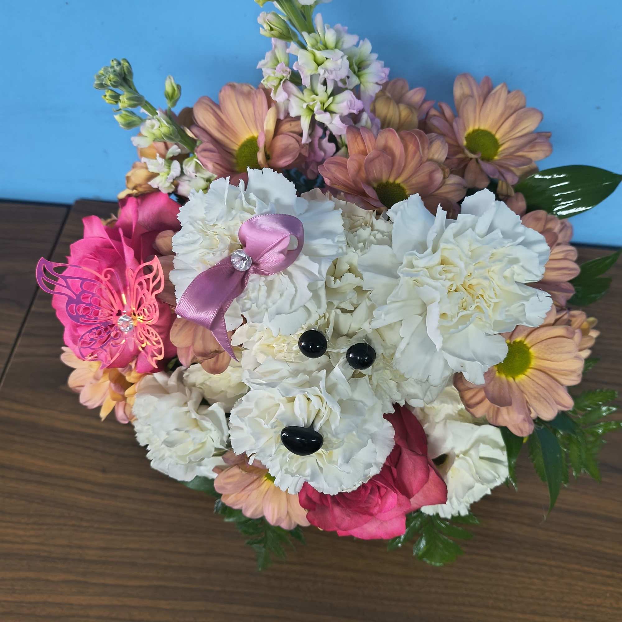 A cheerful white carnation puppy greets the recipient-an imaginative flower arrangement perfect