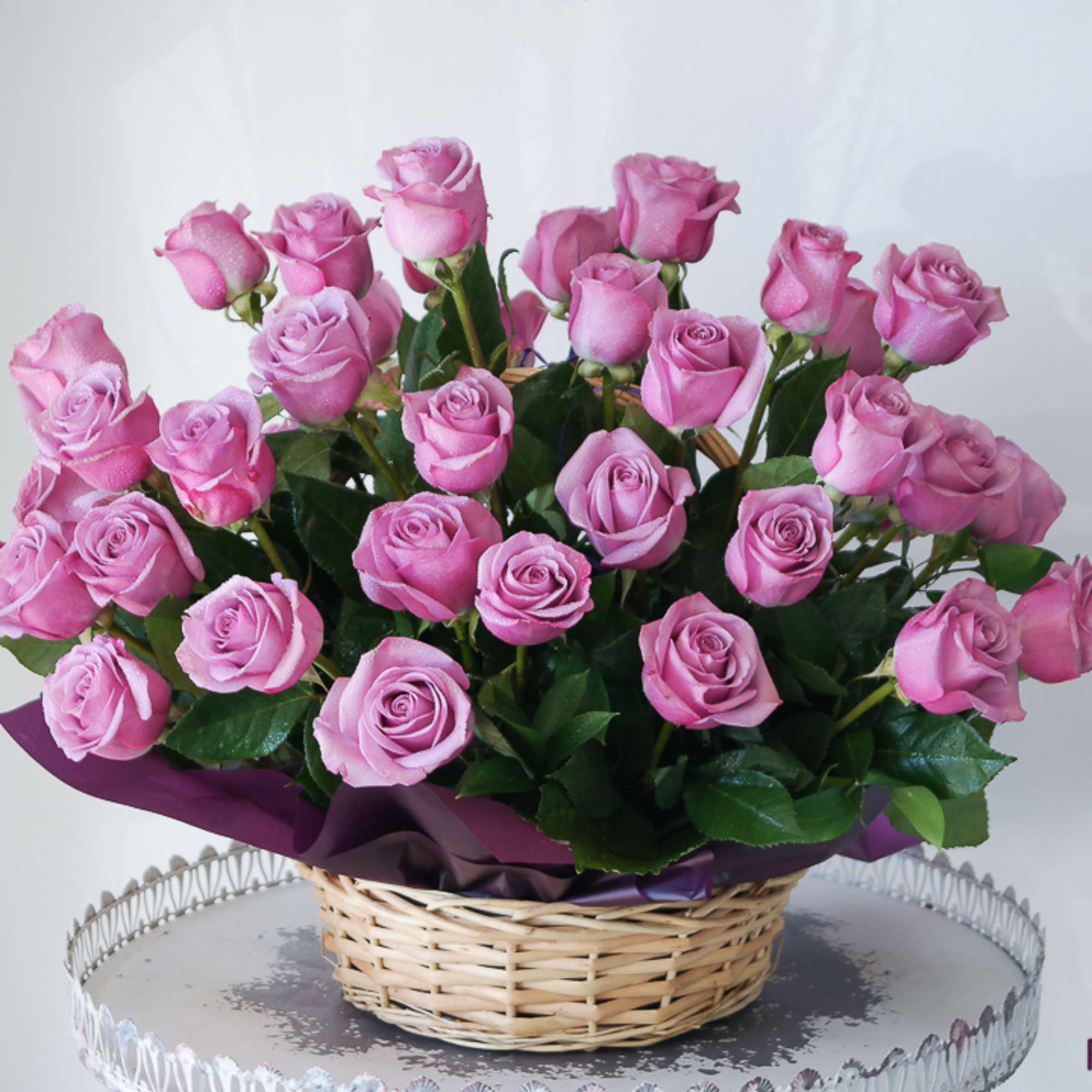 Three dozen purple roses arranged in a basket. 
