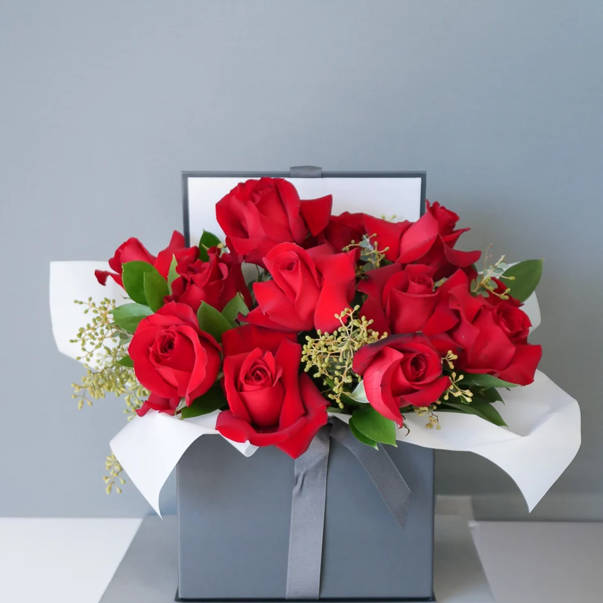 A romantic, modern floral gift box. This arrangement includes red roses and