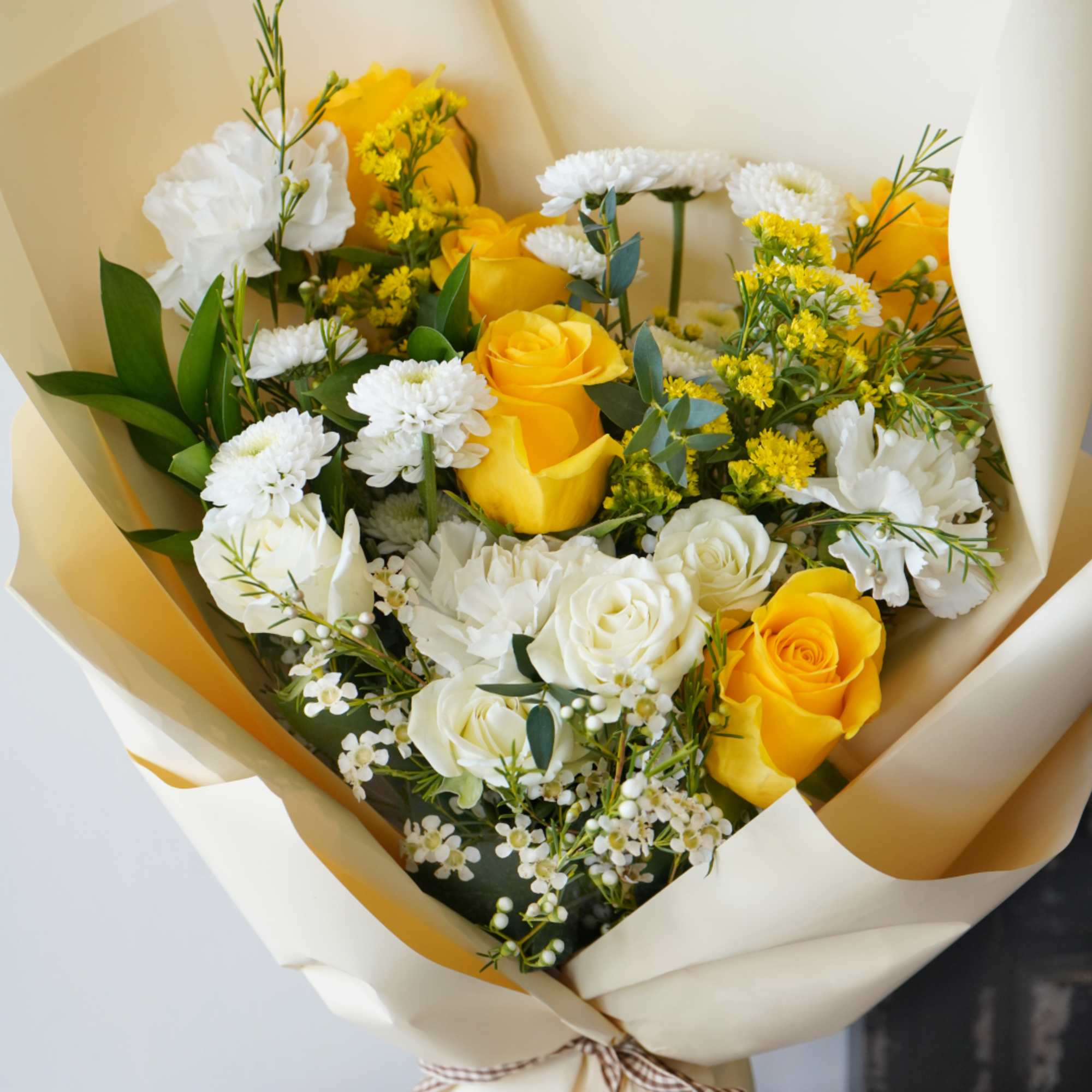 A radiant blend of sunny yellow roses, delicate white spray roses, and