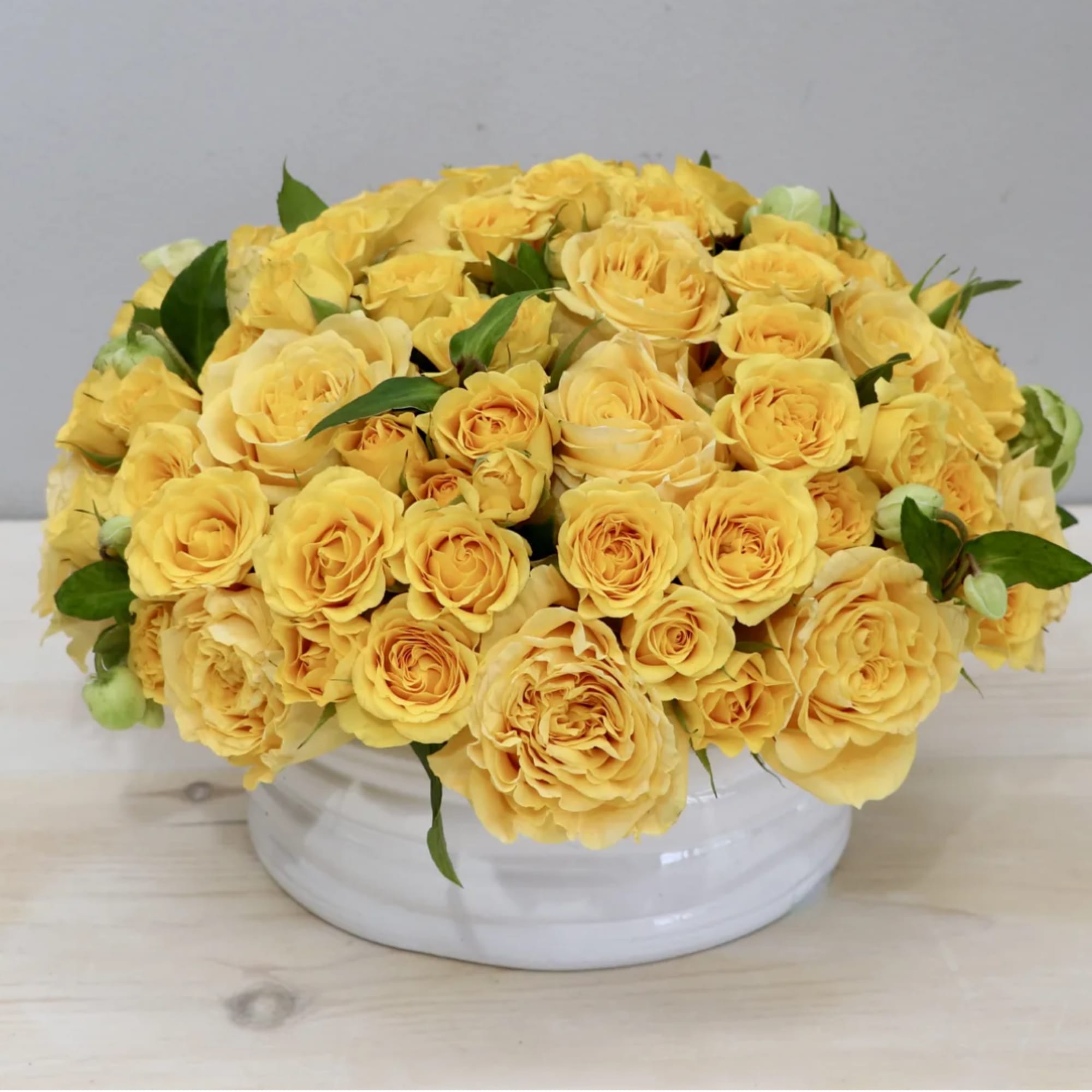 Over two dozen joyful yellow Roses in a round vase. These bright