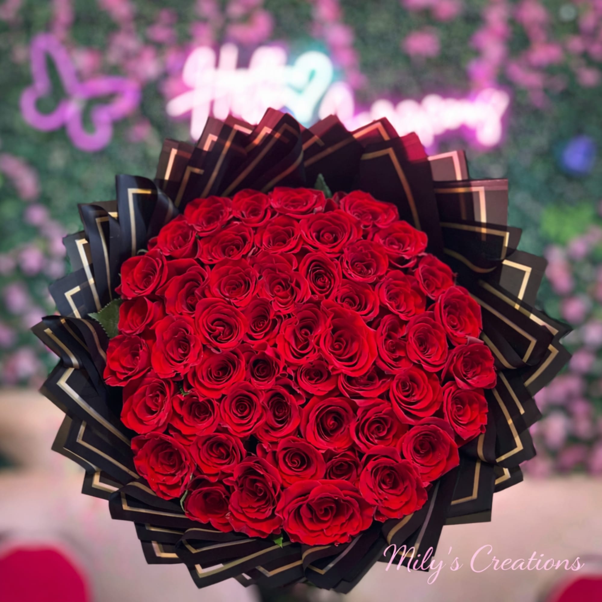 Large round bouquet of tightly clustered red roses wrapped in black and gold paper