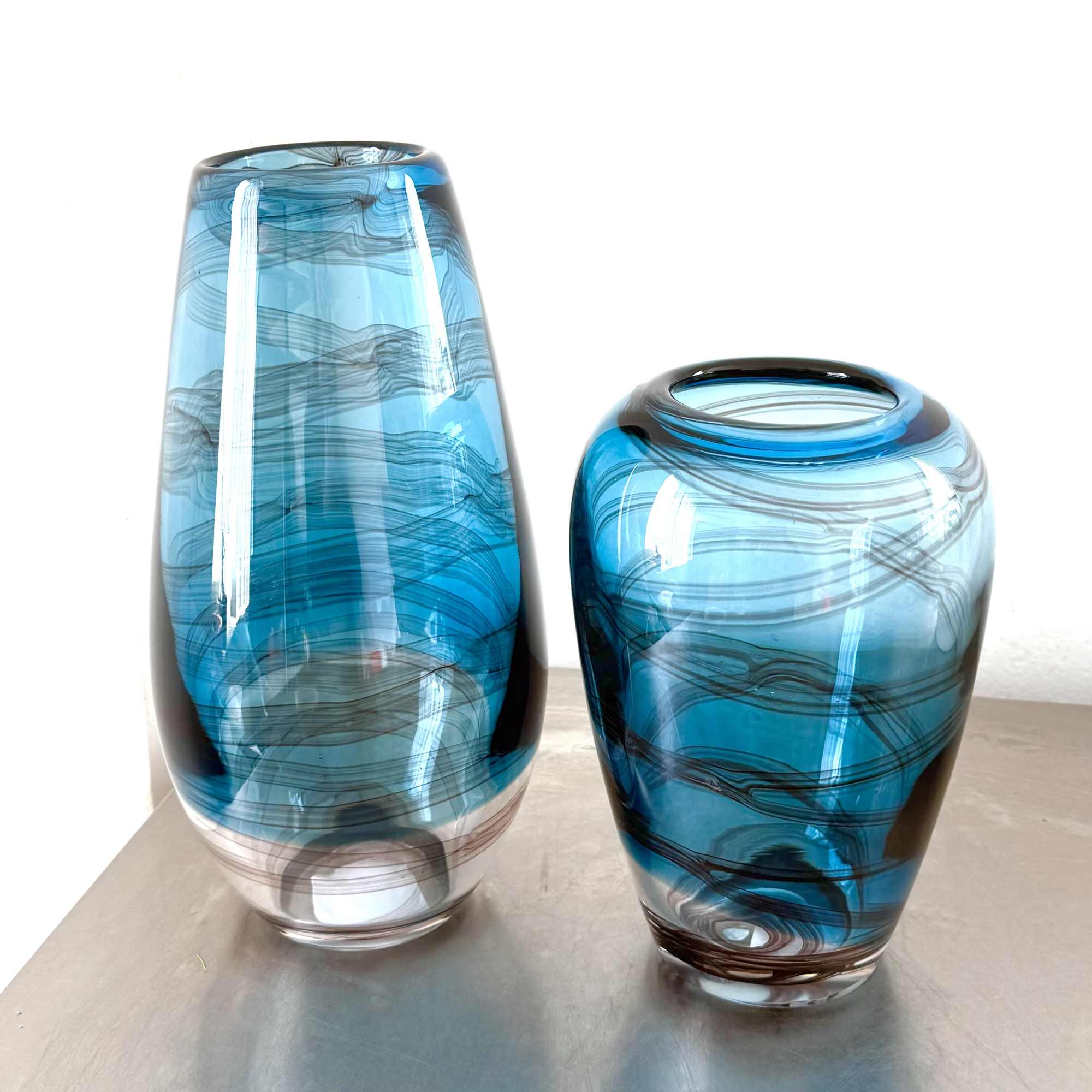 Designed in a striking blue art glass vase with smoky, ribbon-like swirls