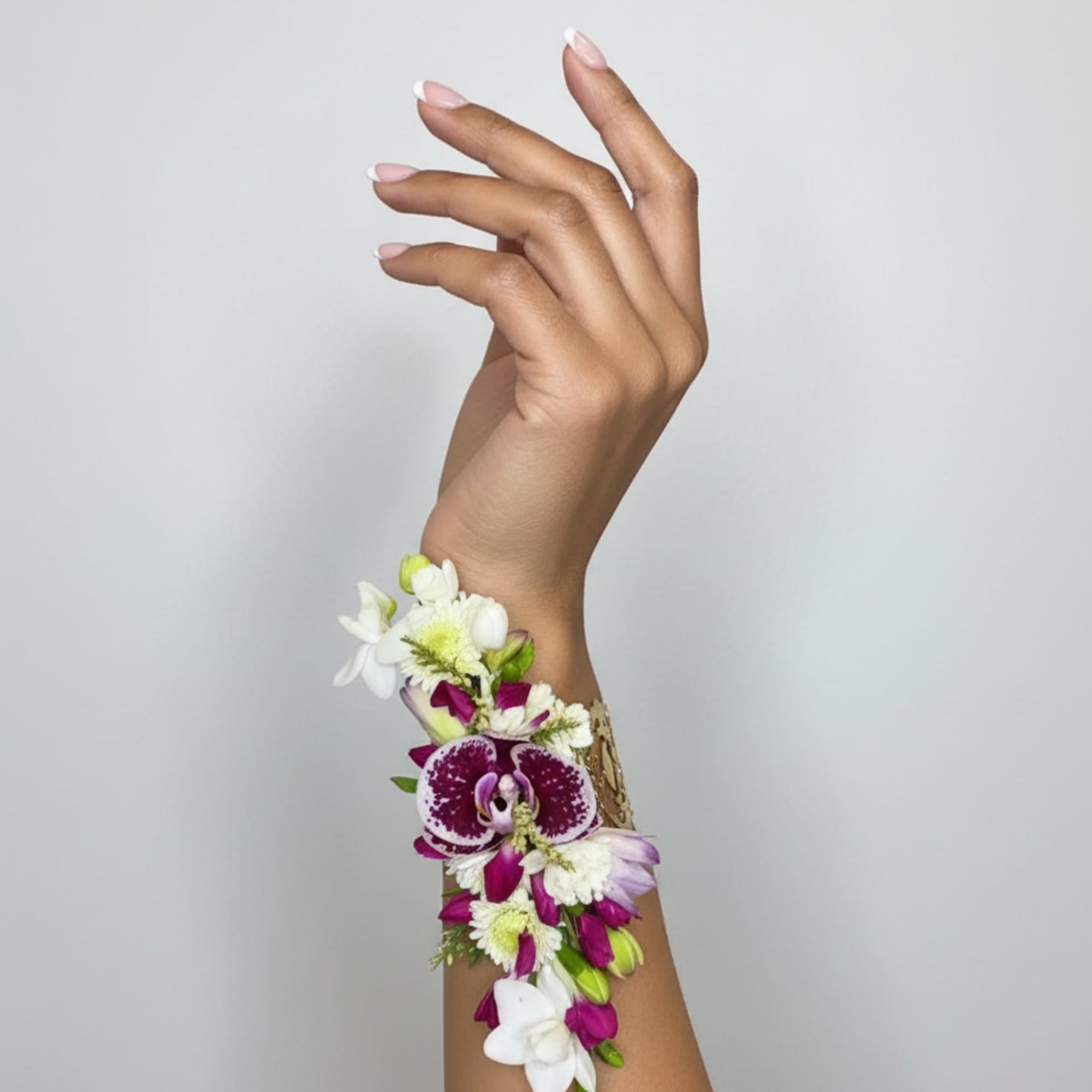 Purple and white orchid wrist corsage on a raised hand