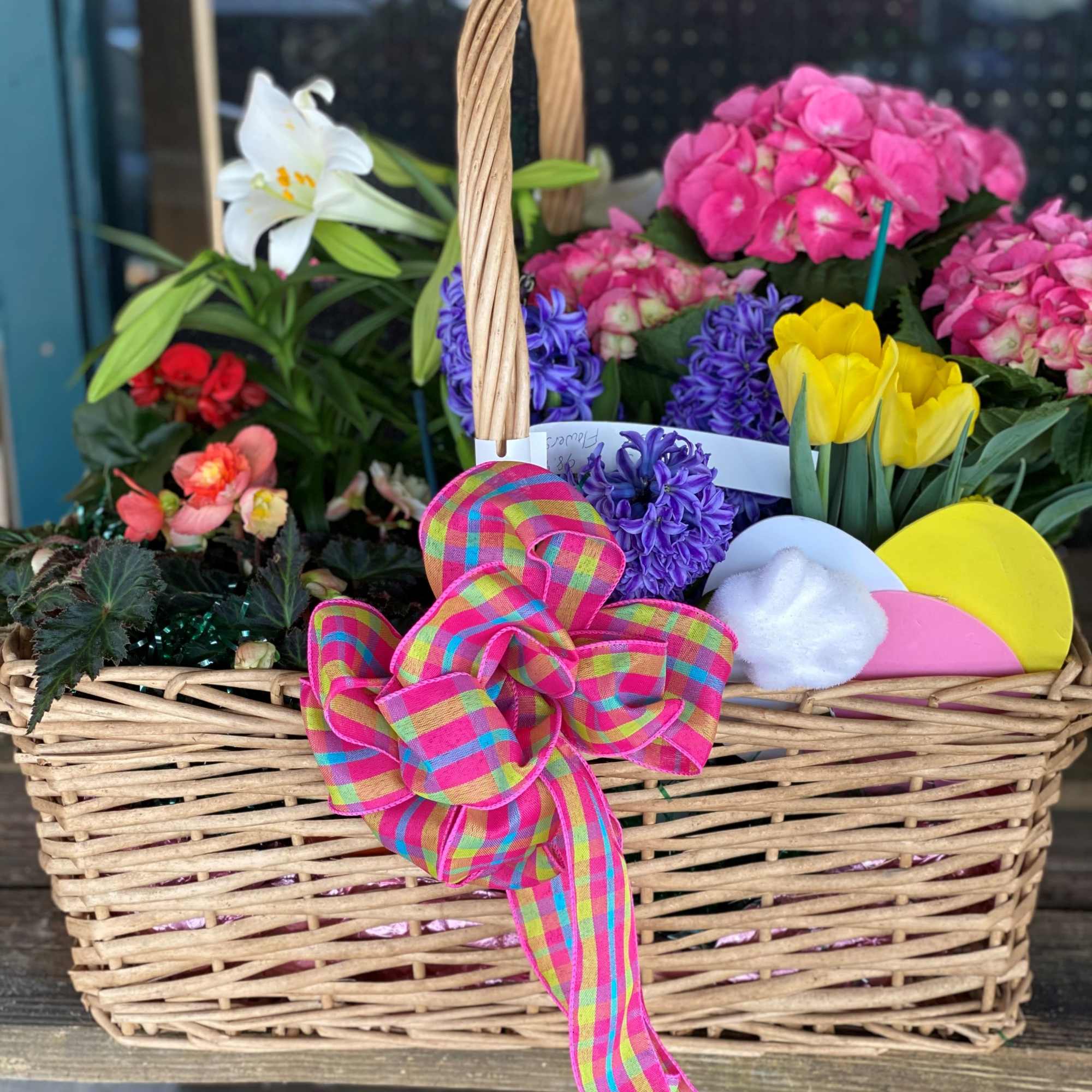 A large basket filled with a variety of flowering plants. Colors &amp;