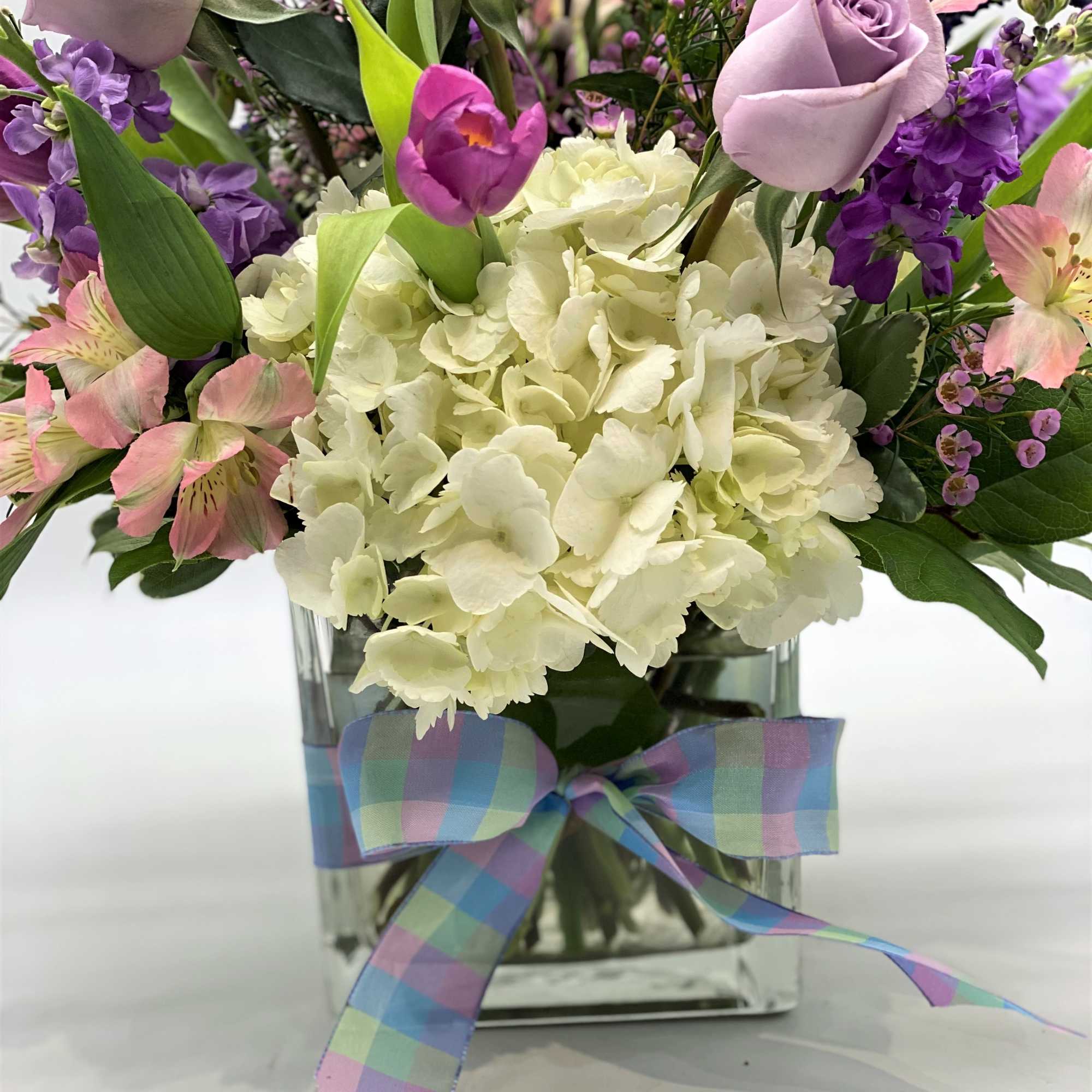 A beautiful glass cube filled with white hydrangeas and various shades of