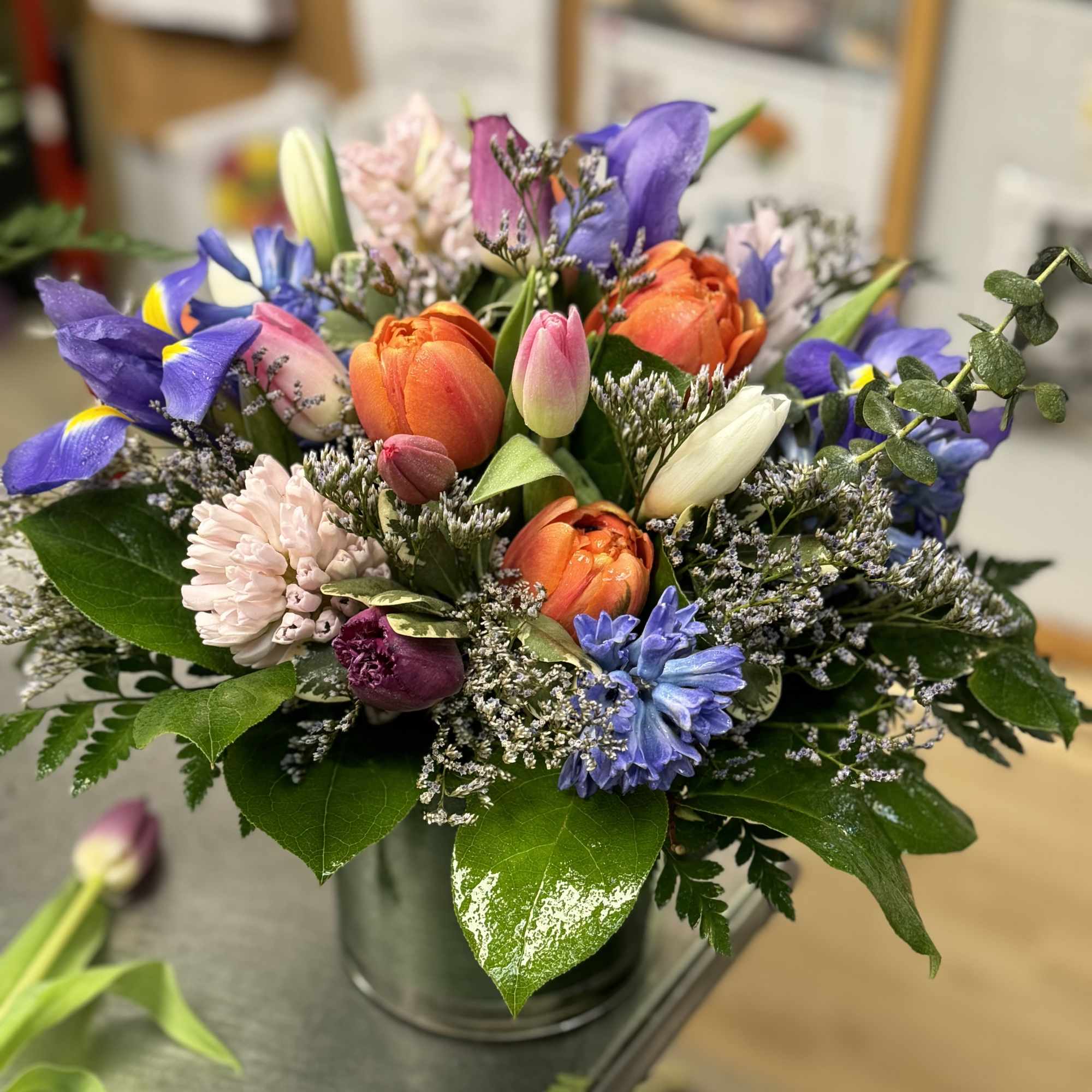 Colorful arrangement of tulips, irises, and other spring flowers in a metal vase