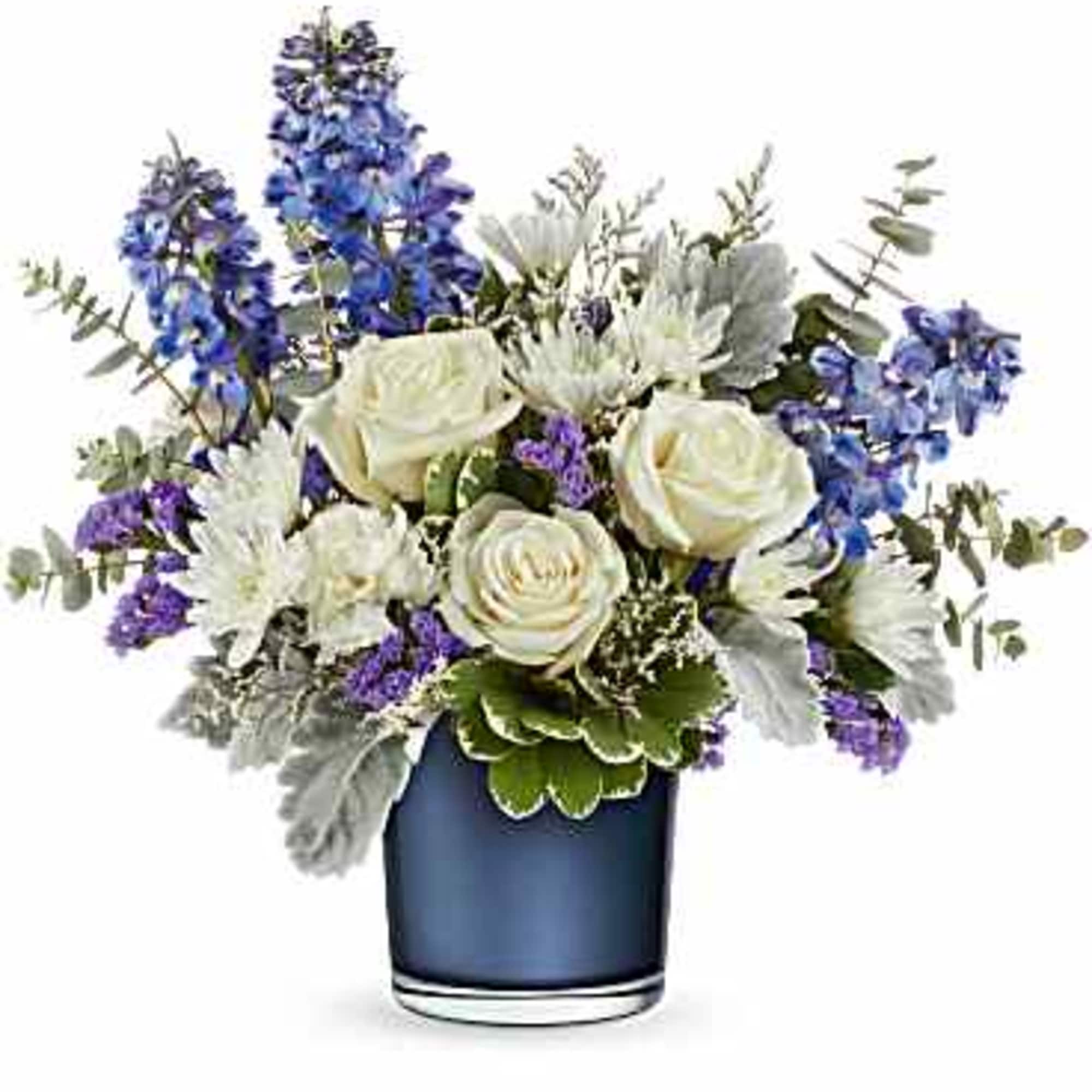 Arrangement of white roses and blue delphinium in a dark blue glass vase with purple accents.