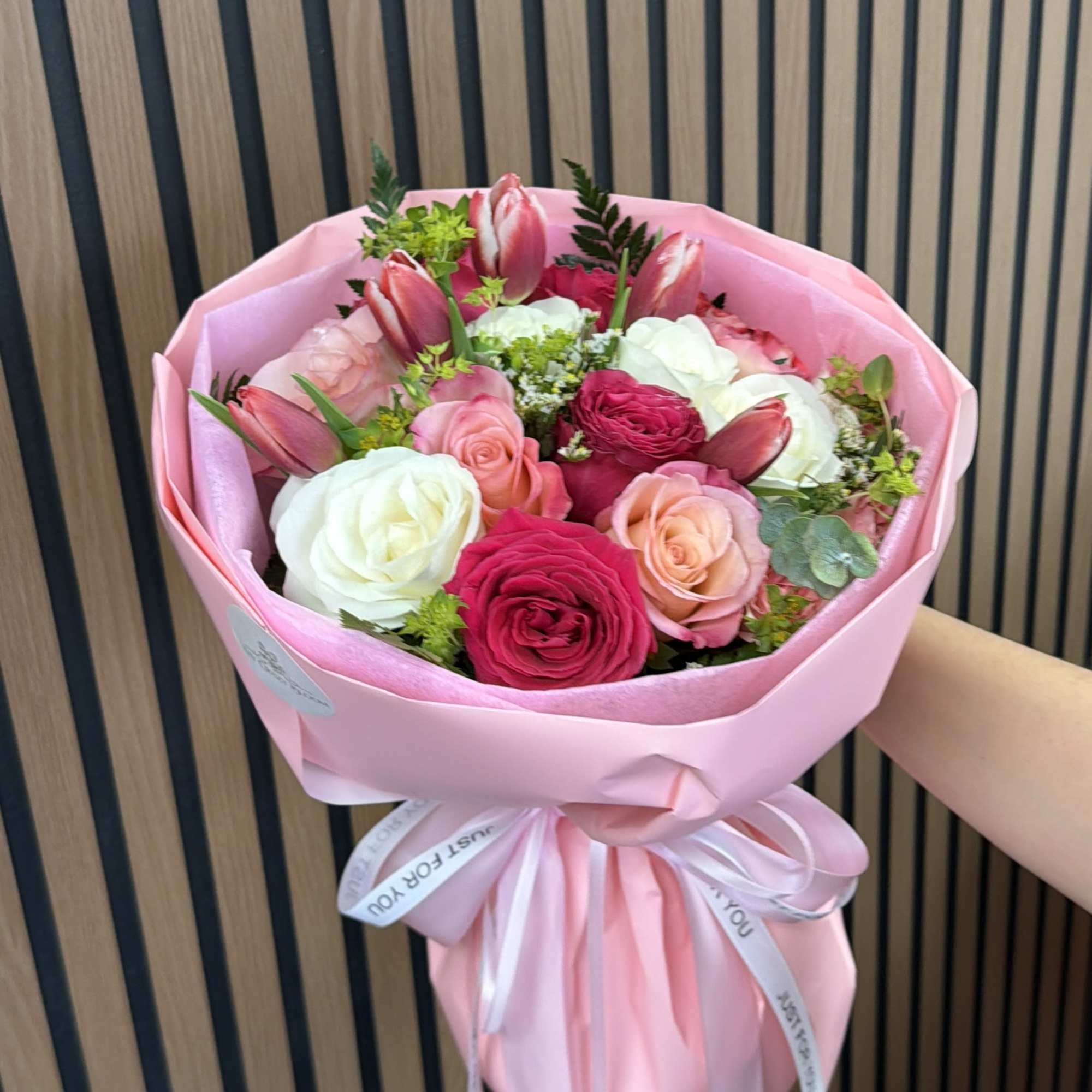 Pink bouquet of roses and tulips wrapped in pink paper