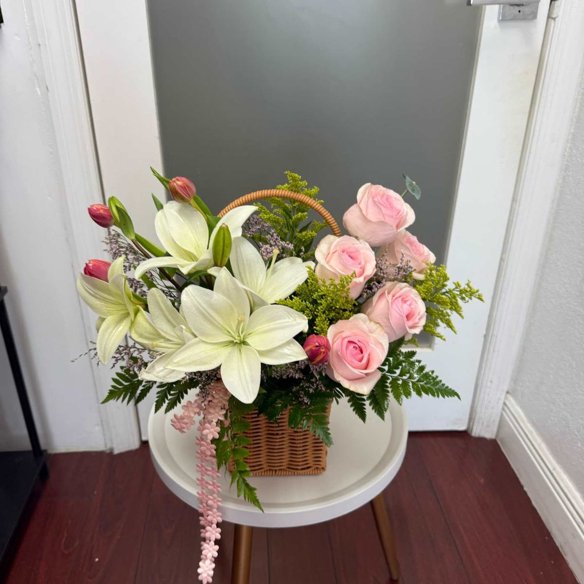 Basket arrangement of pink roses and white lilies
