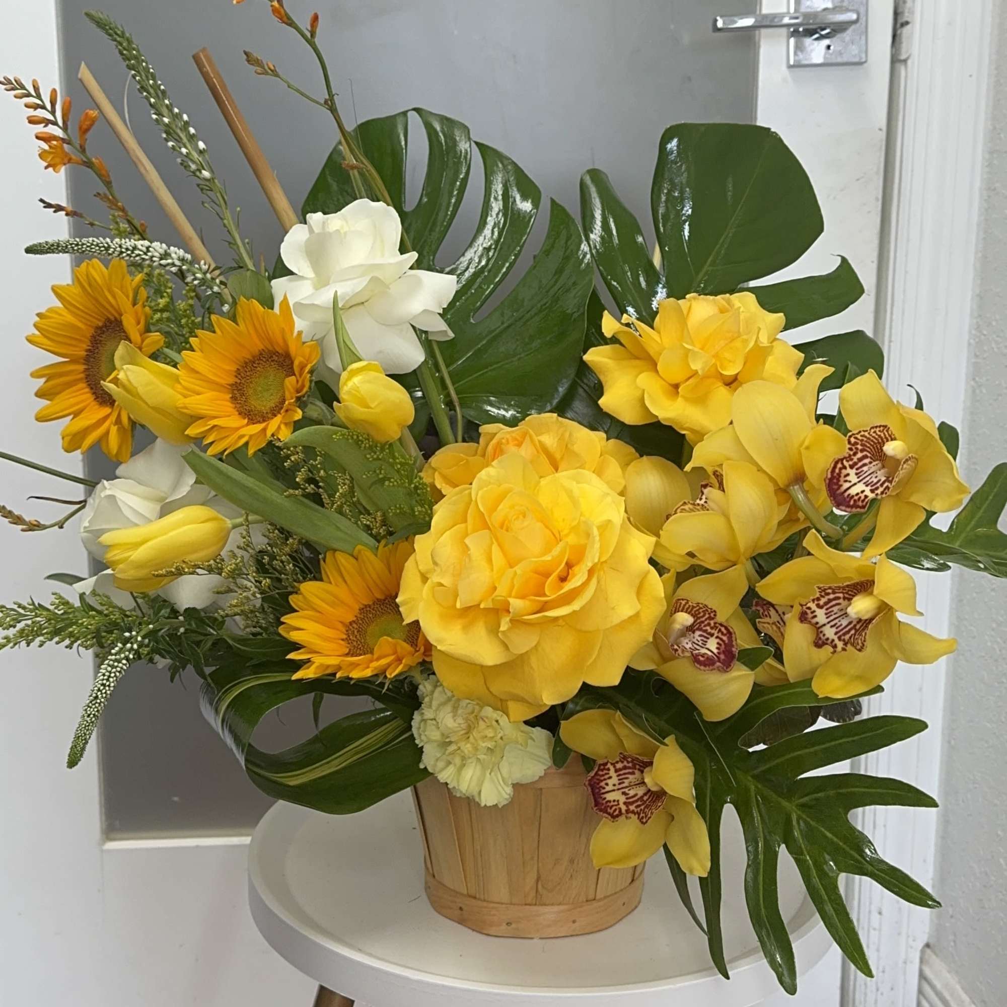 Yellow and white floral arrangement in a wooden basket