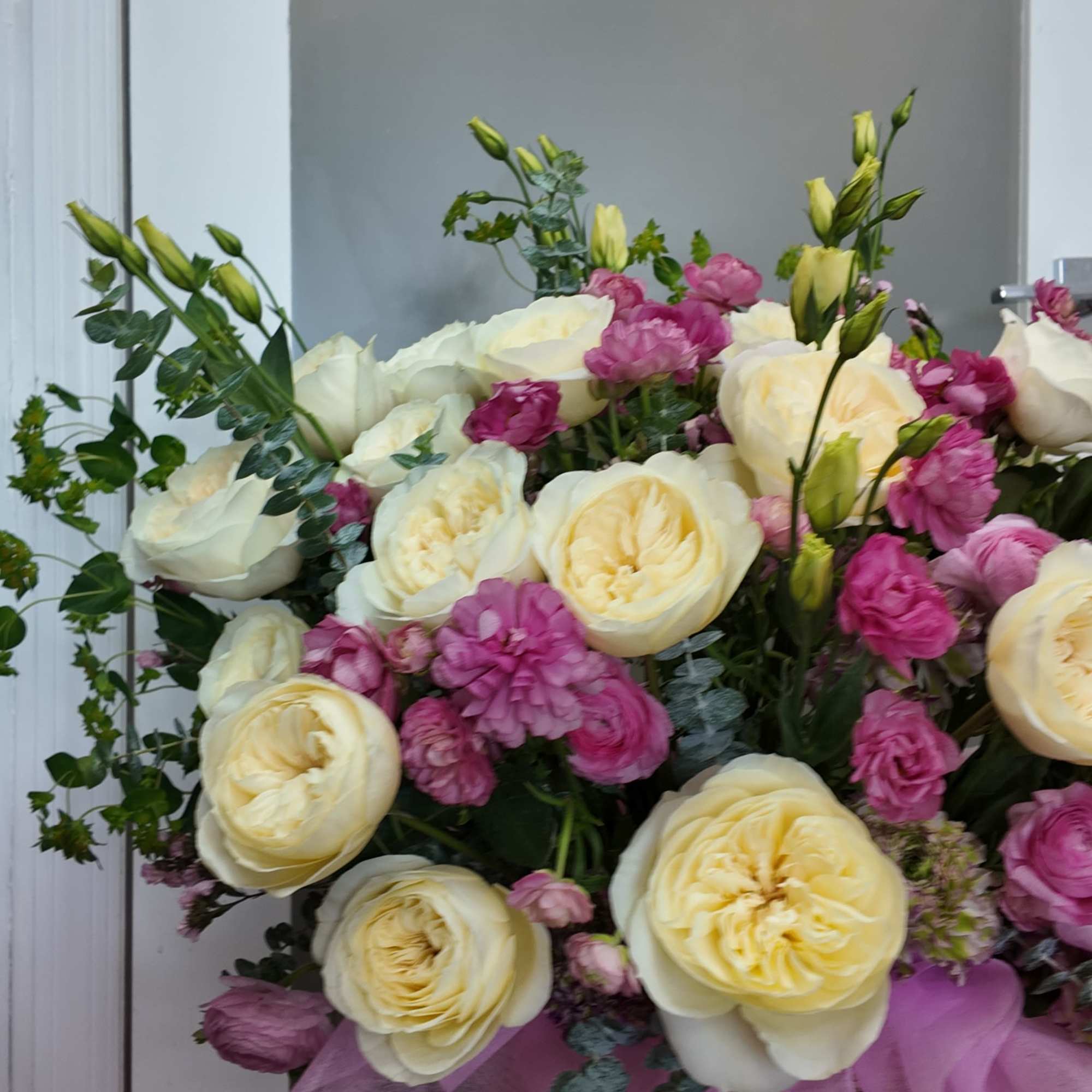 Bouquet of cream roses and pink flowers in a pink basket