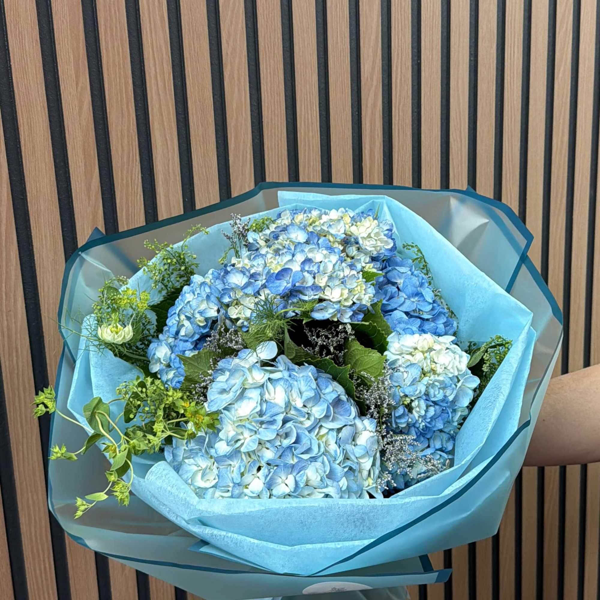 Blue hydrangea bouquet wrapped in turquoise paper
