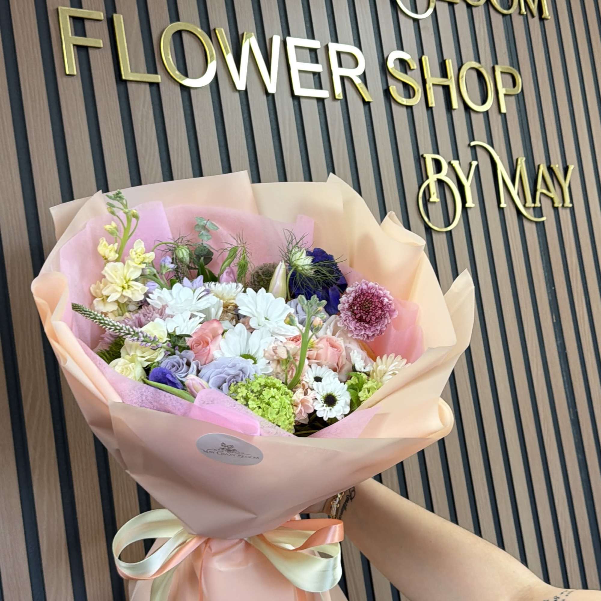 Pastel mixed flower bouquet wrapped in pink paper with ribbon