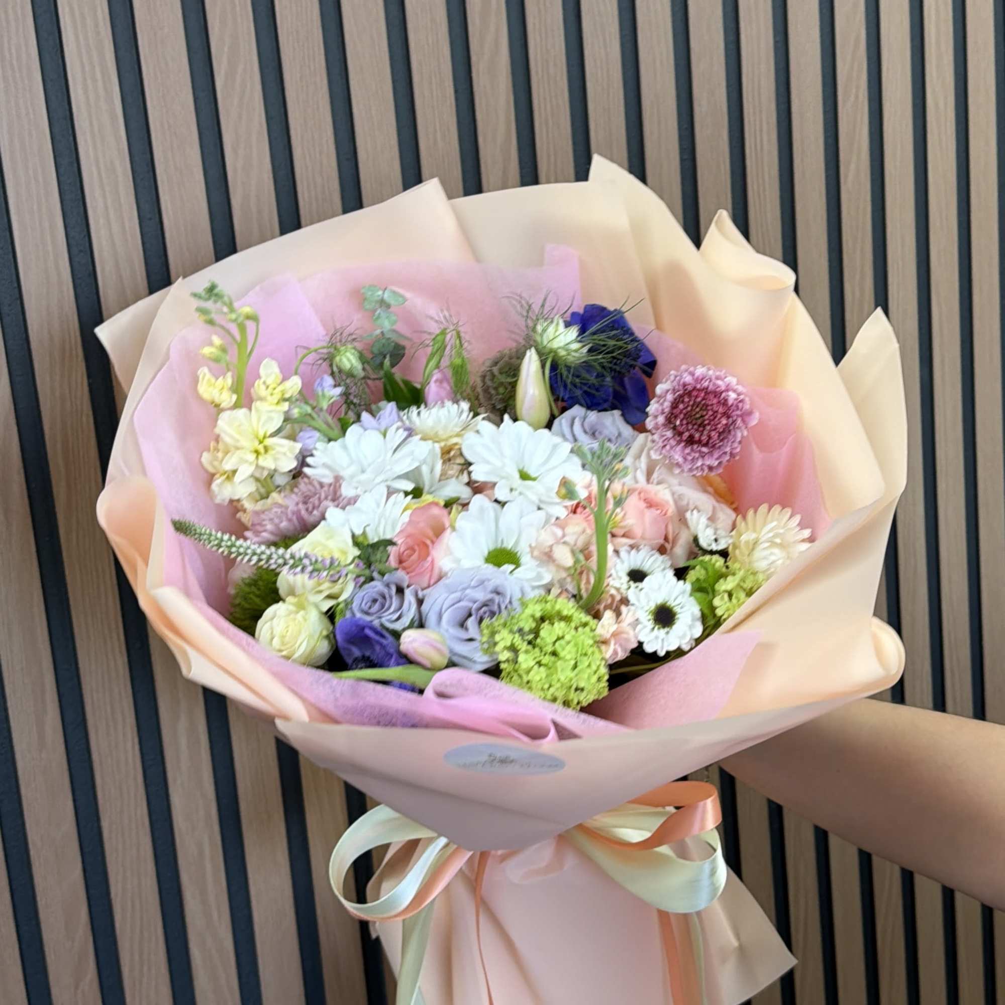 Pastel mixed bouquet with roses, daisies, and ribbon wrap