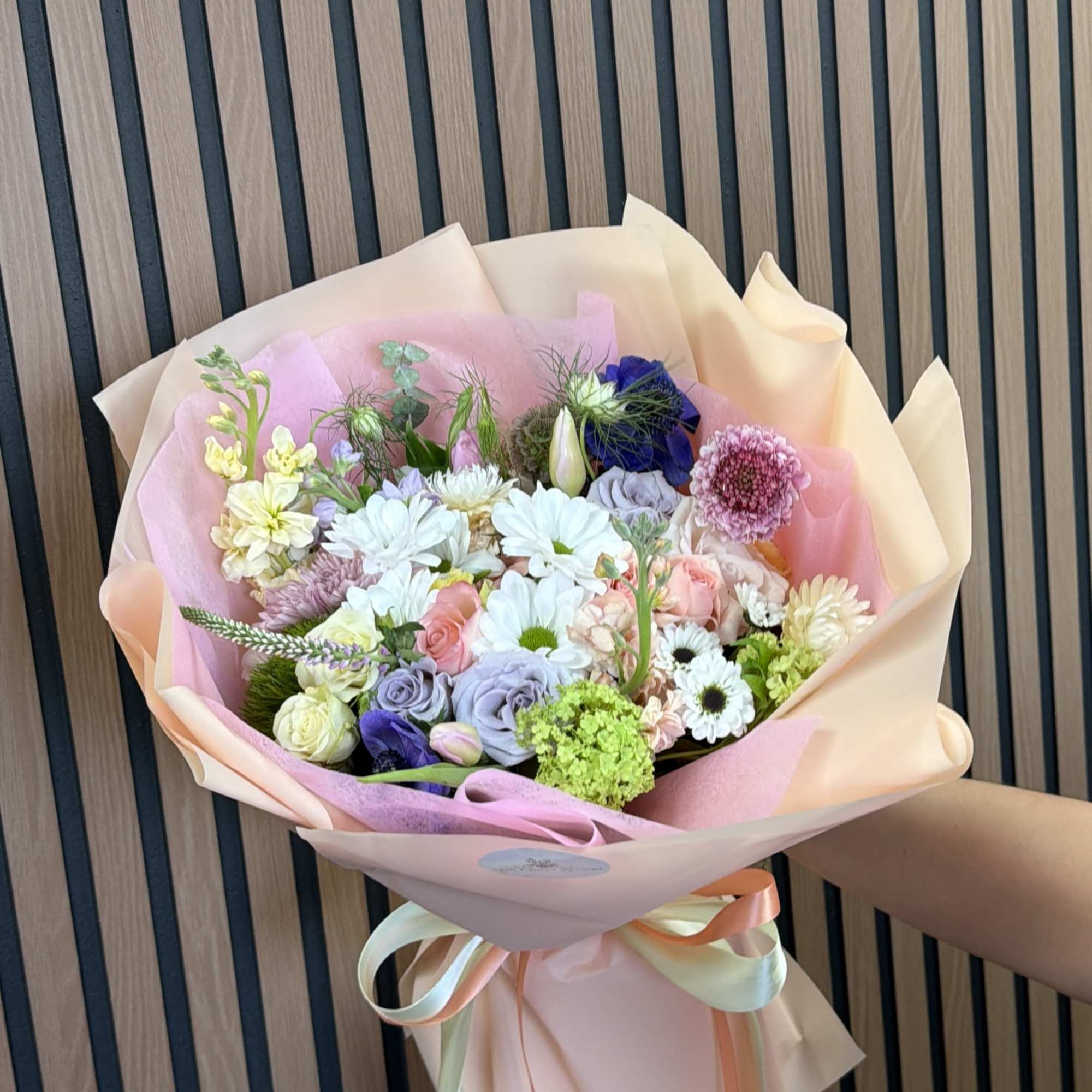 Pastel mixed flower bouquet wrapped in pink paper with ribbon