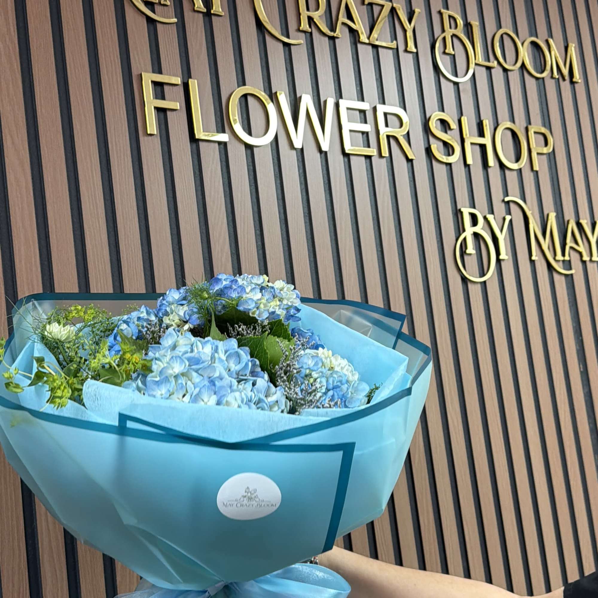 Blue hydrangea bouquet wrapped in turquoise paper with a ribbon