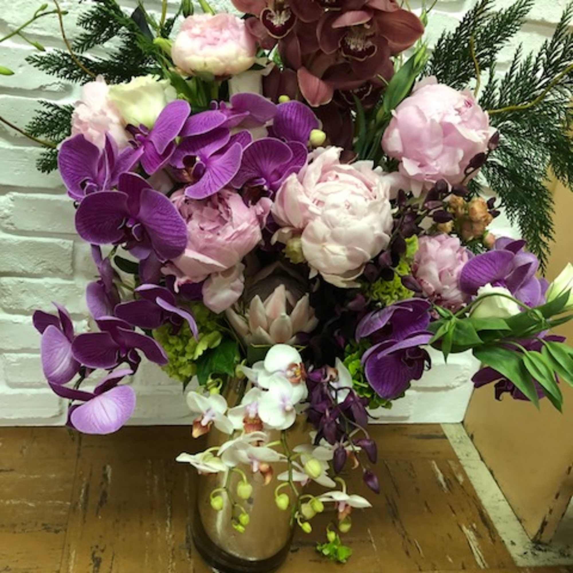 Mixed orchid and peony arrangement in a vase
